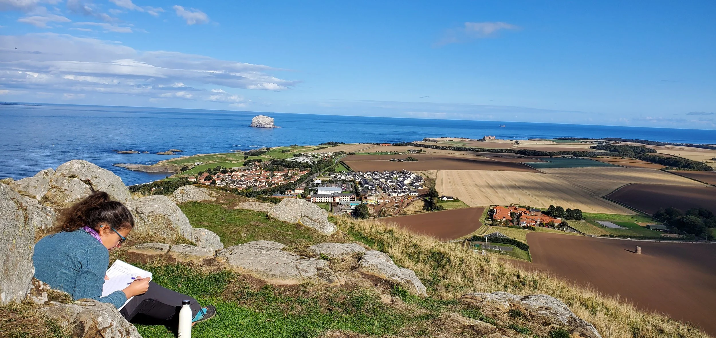 Lucie Aidart écrit son livre intuitif L'Envol sur les hauteurs de North Berwick en Écosse, face à la mer et au ciel bleu