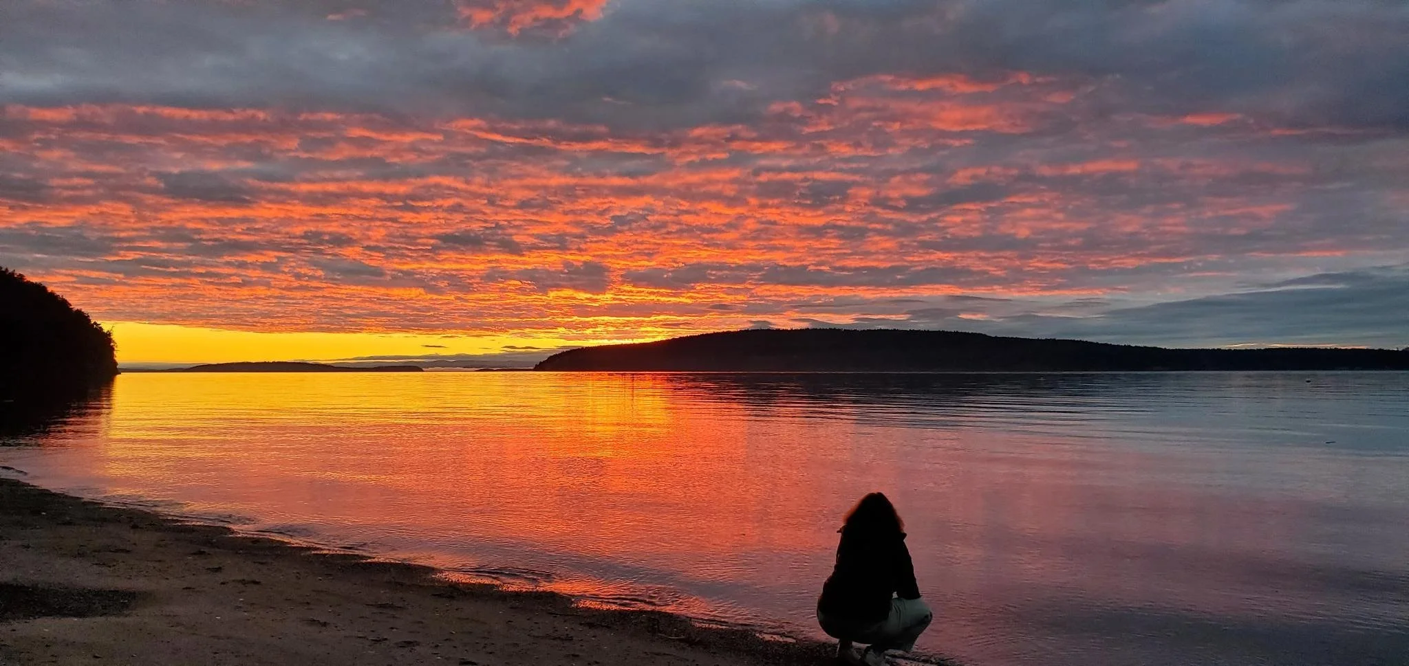 Lucie Aidart in the midst of a pink and orange sunset on Orcas Island, USA