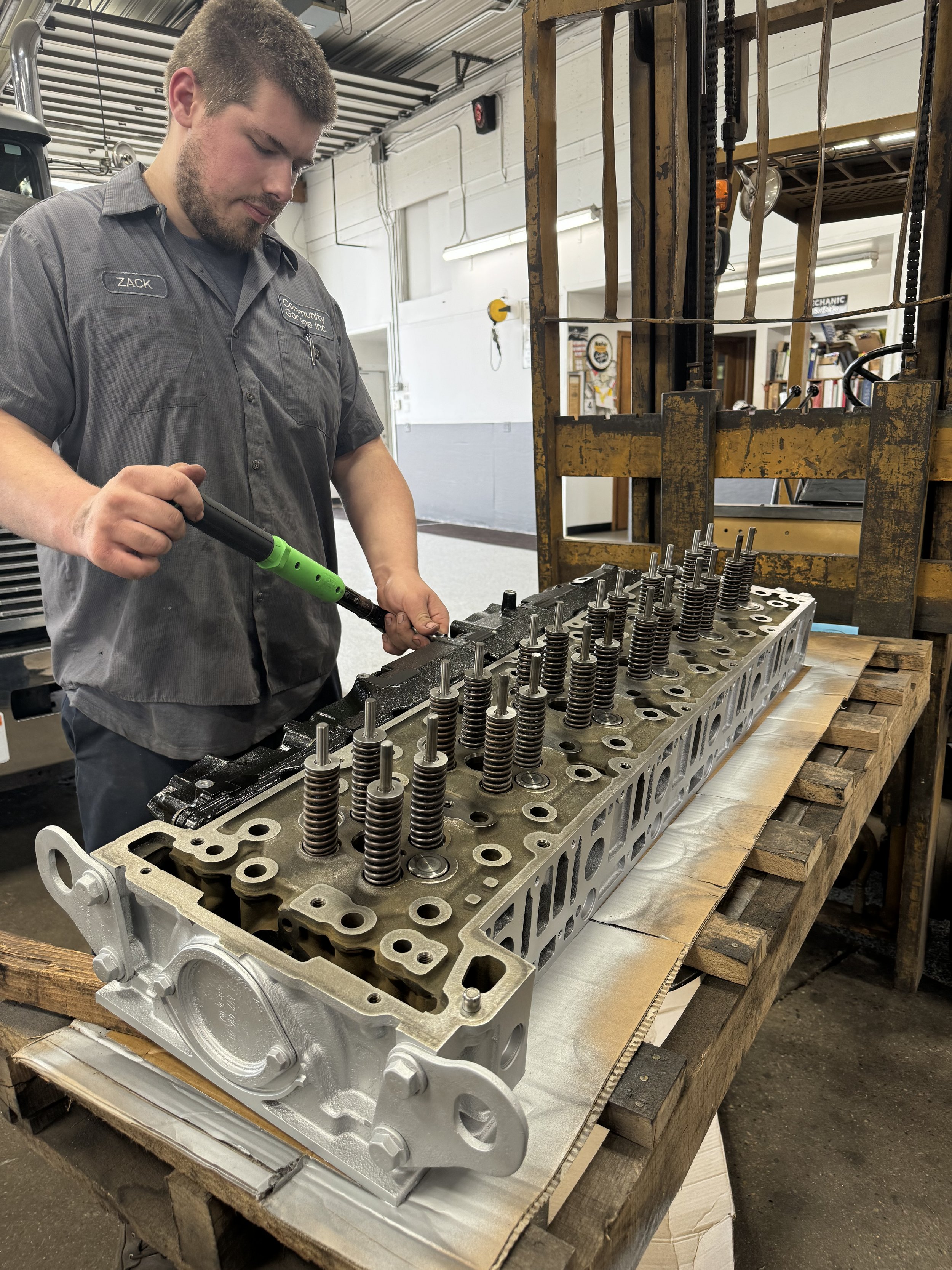 A certified diesel mechanic examining cylinder head and torquing valve springs to factory spec.