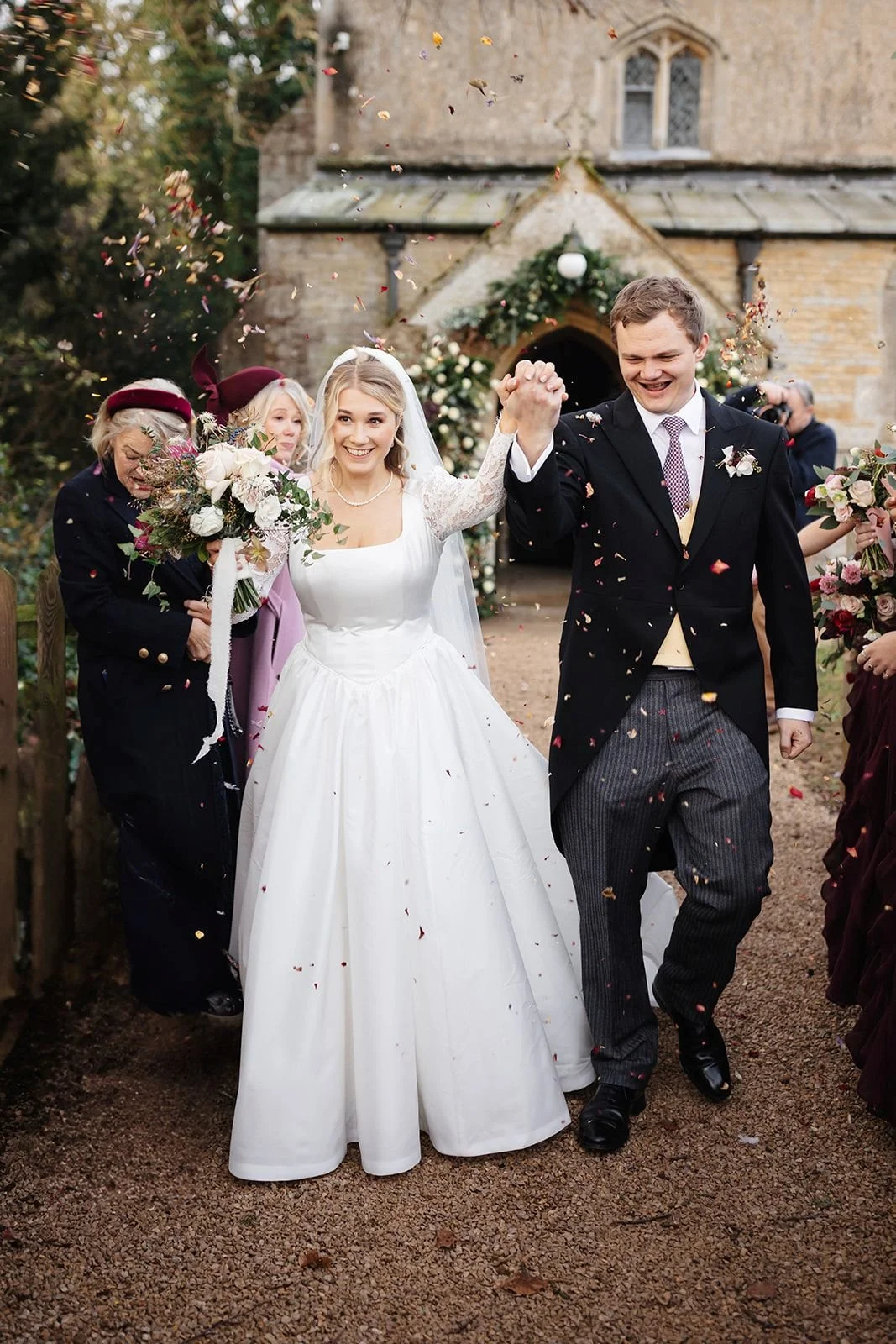 bride and groom walking through confetti line with bride holding bouquet