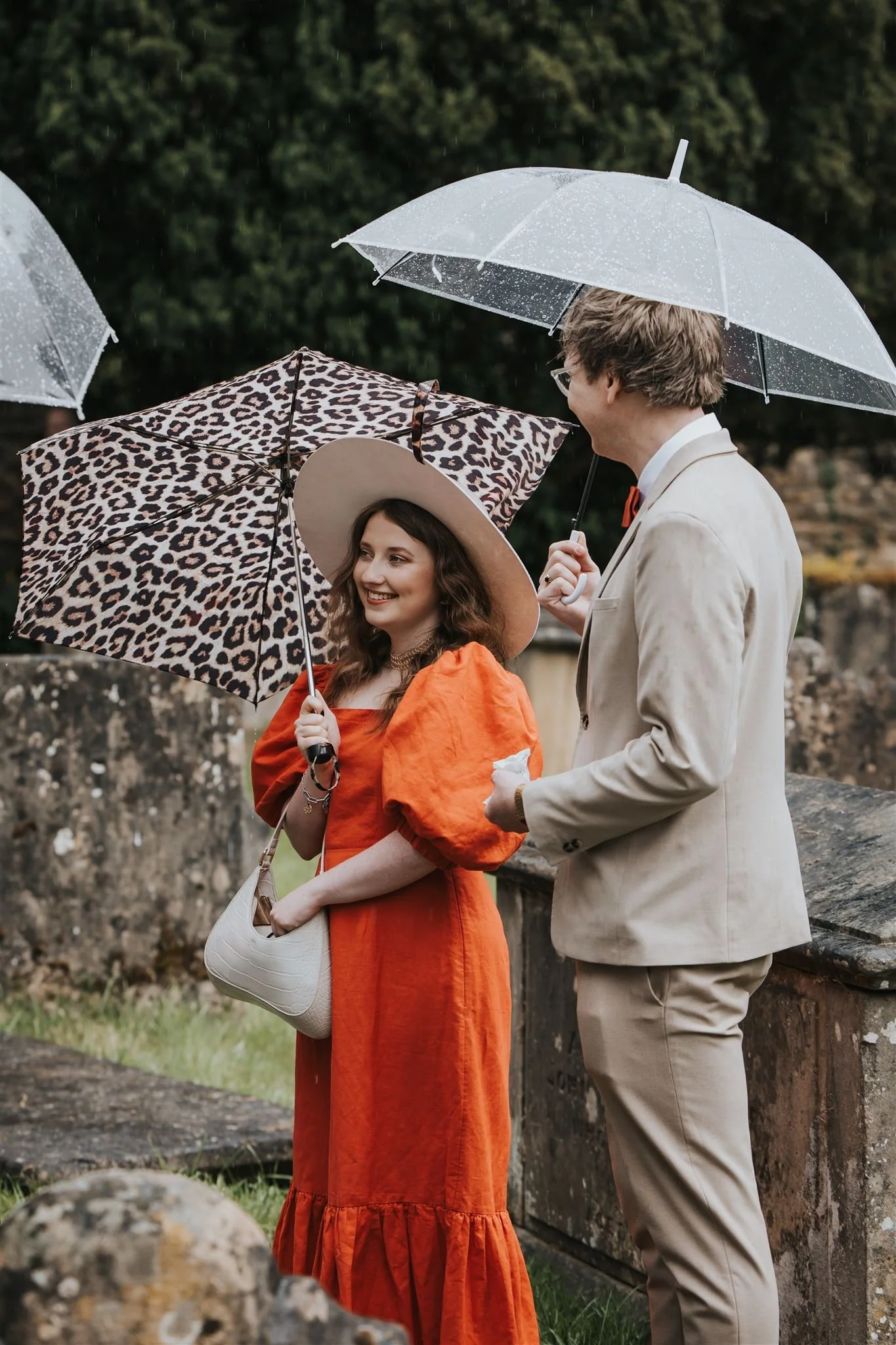 Guests standing outside church wedding ceremony holding umbrellas