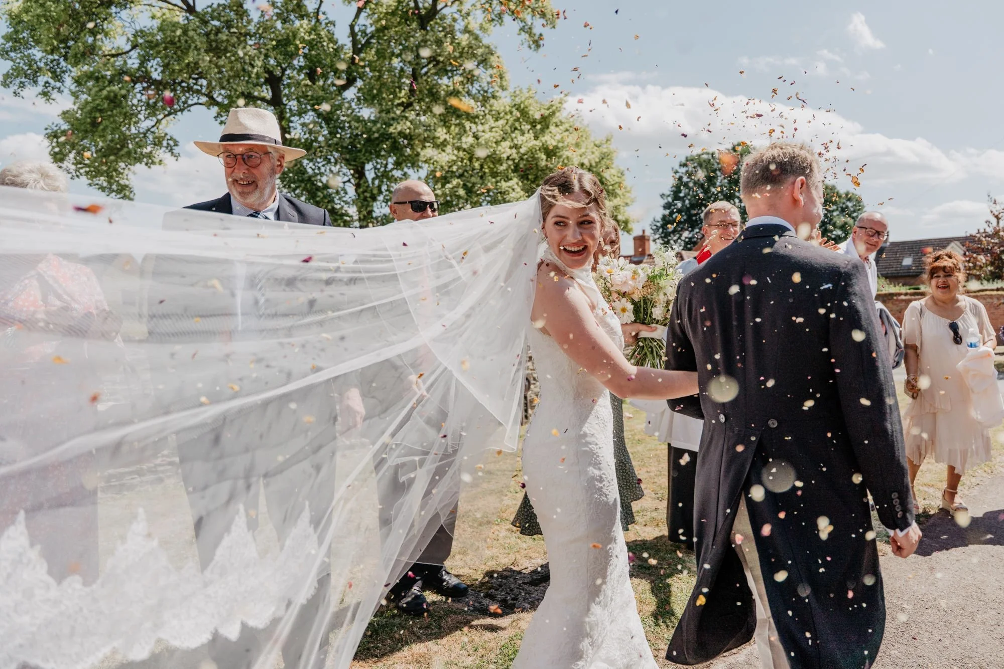 bride and groom during confetti throw with bride's veil blowing