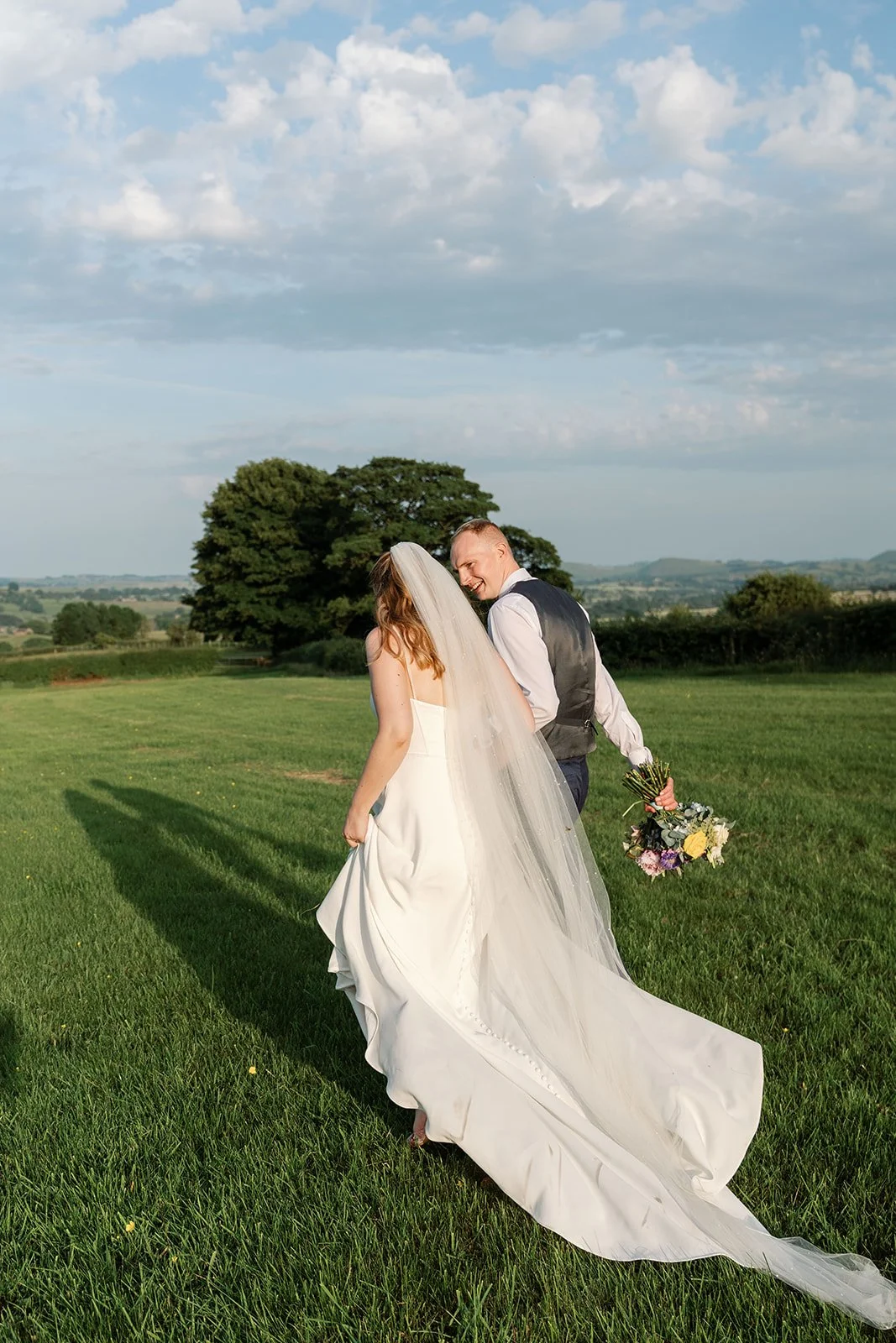 bride and groom walking through field.jpg