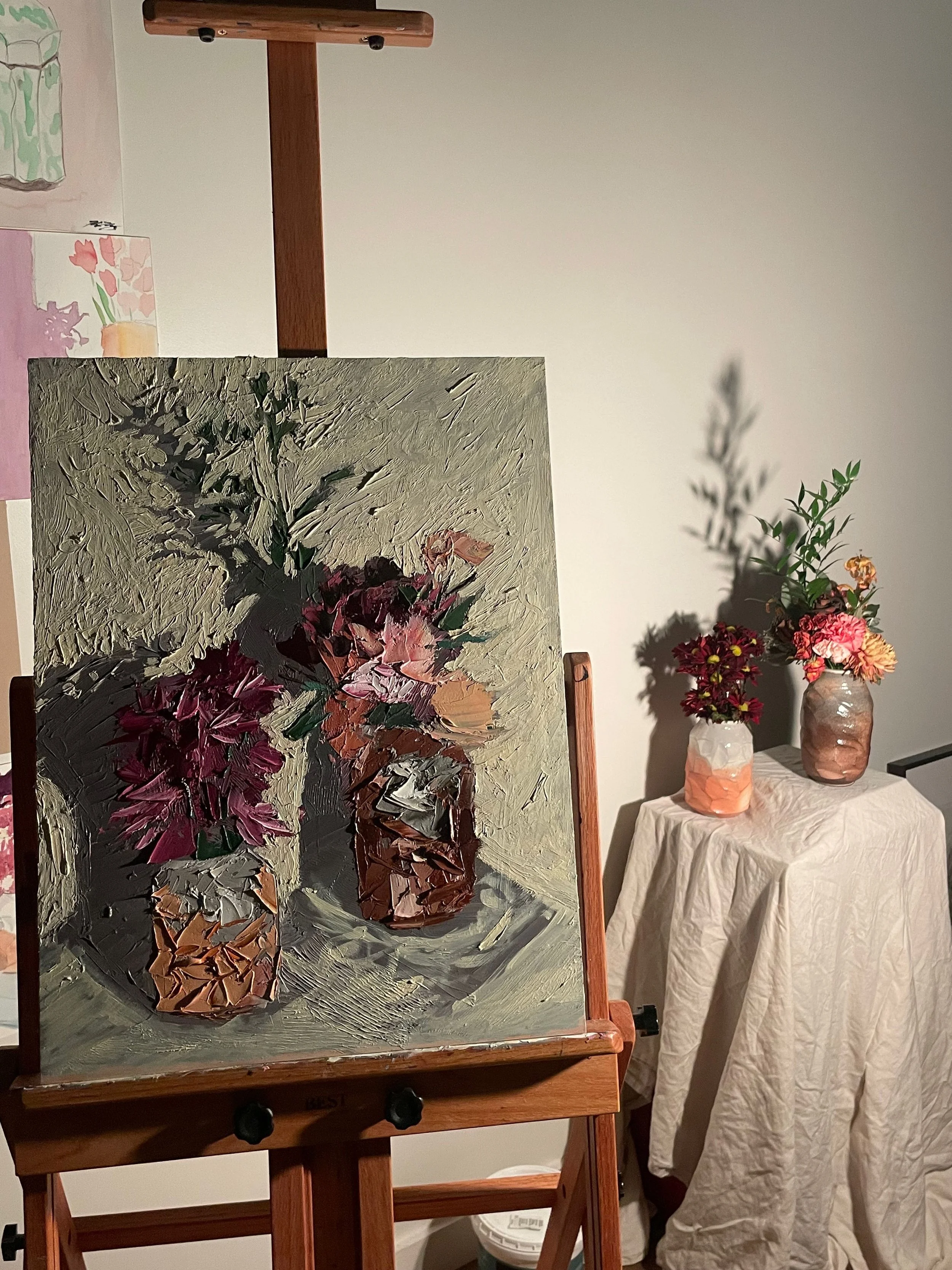 Completed still life painting and the inspiration of a vase with flowers on a plinth.