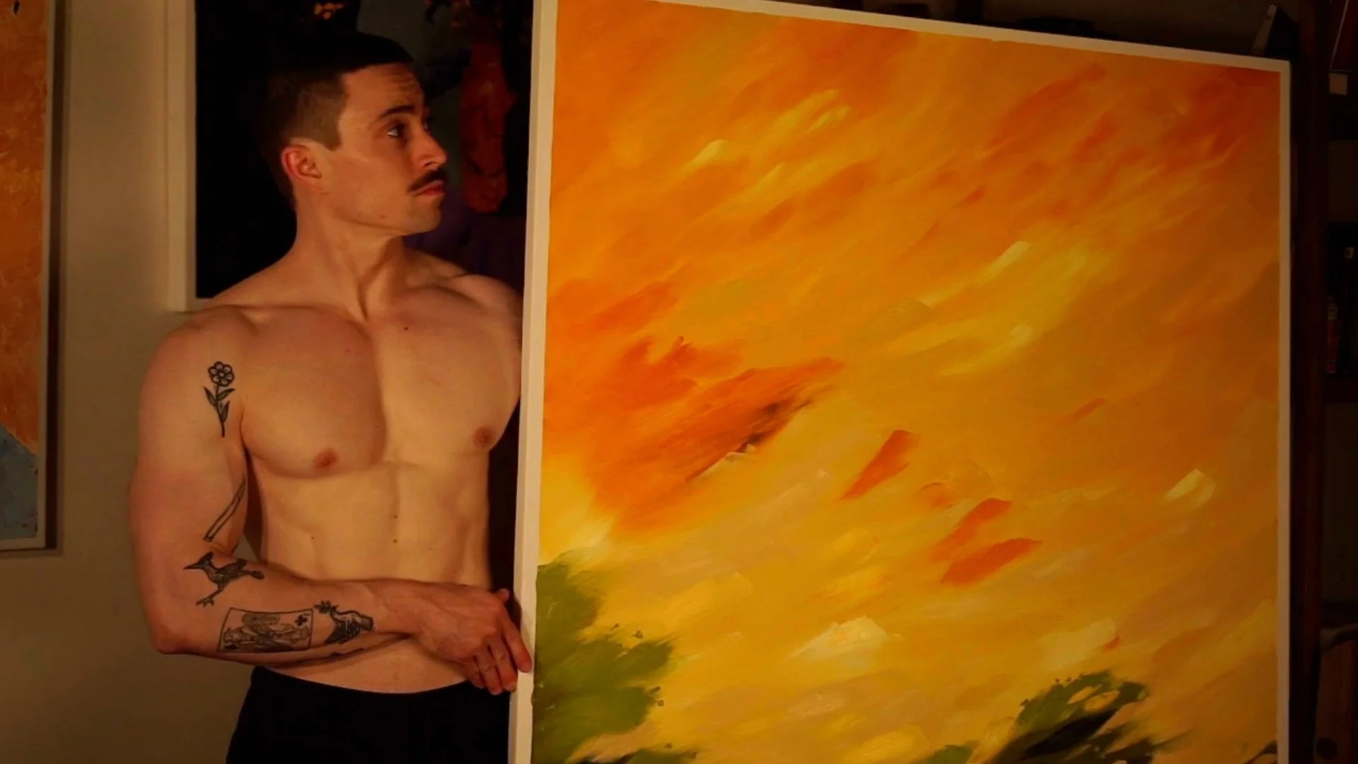 Kevin Koza holding one of his orange abstract oil paintings