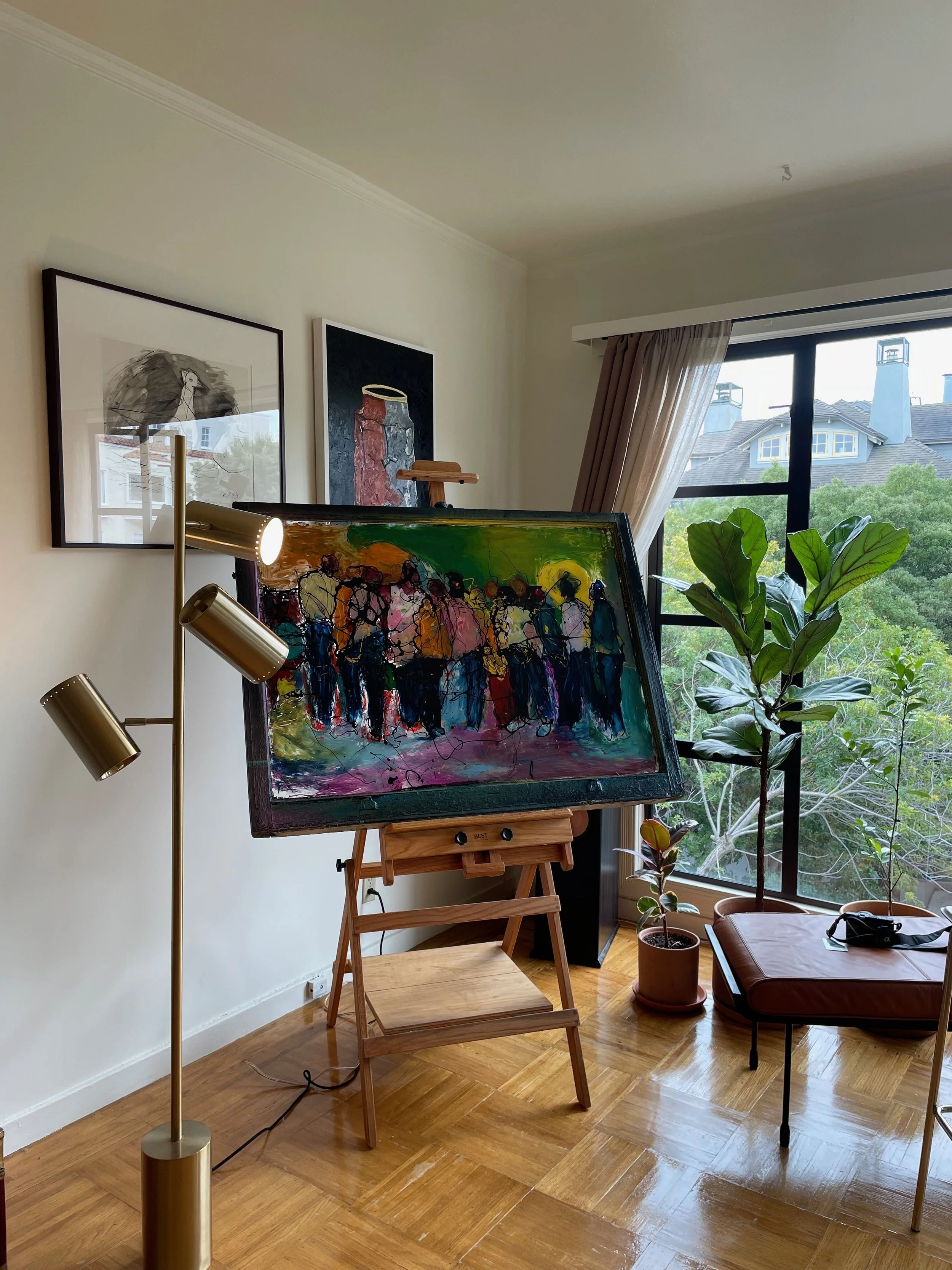 Indoor studio with a painting on an easel and paintings on the walls in an airy interior.