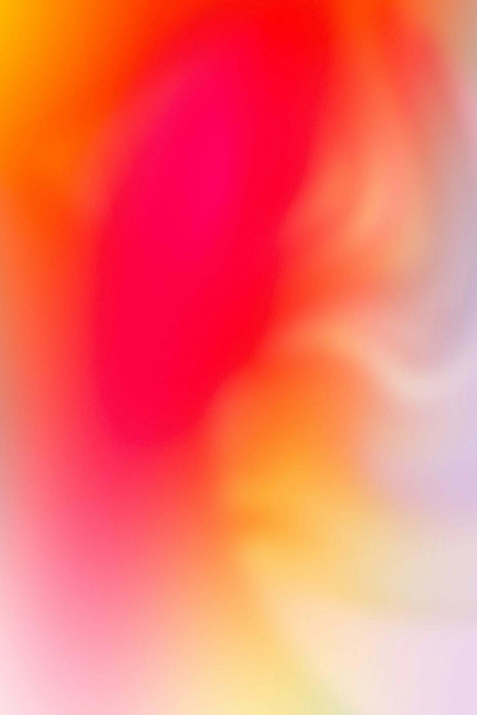 Blurred abstract colorful background with shades of pink, orange, yellow, and purple.