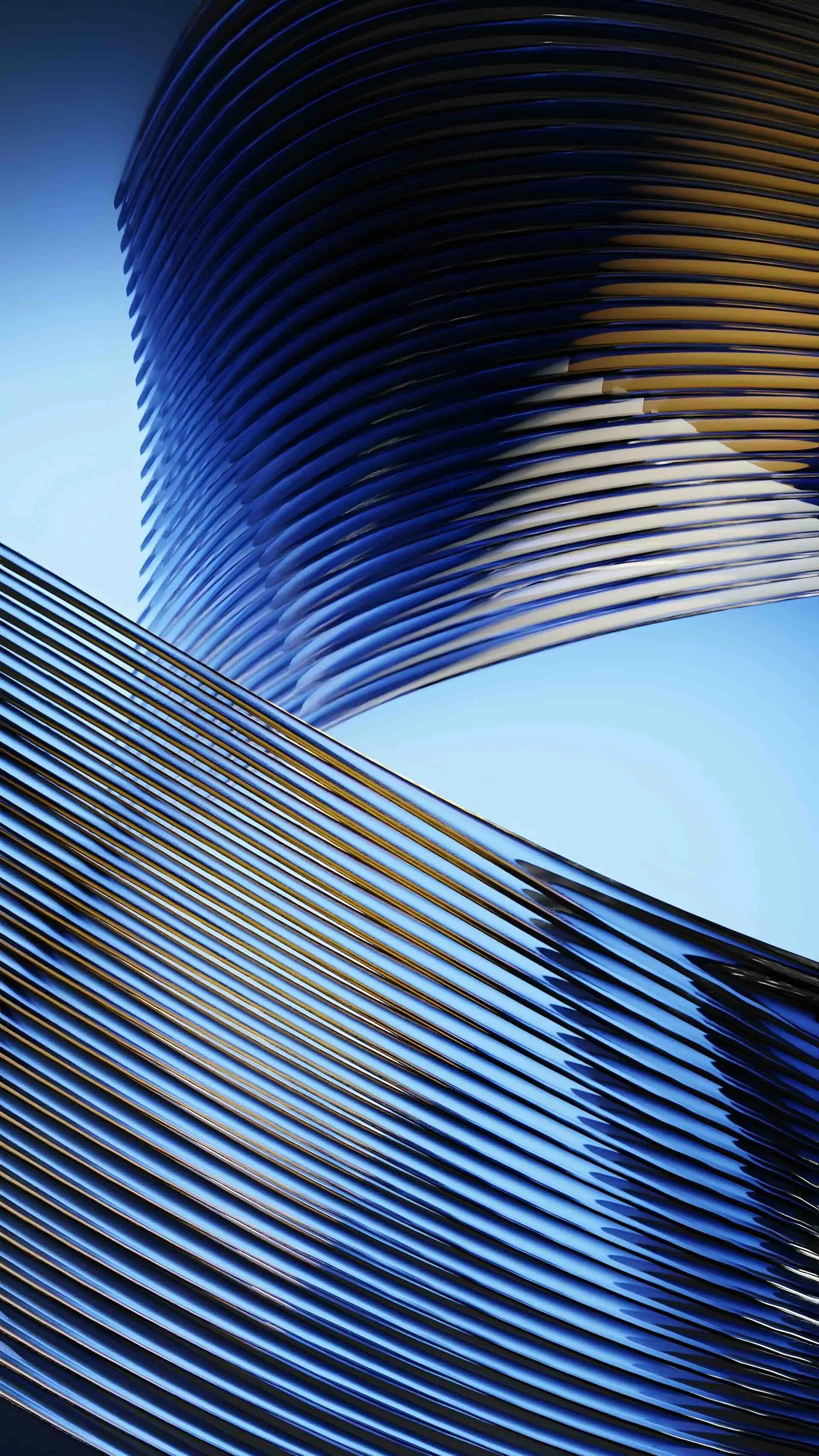 Close-up of a modern building with curved, layered metallic or glass surfaces reflecting the blue sky.