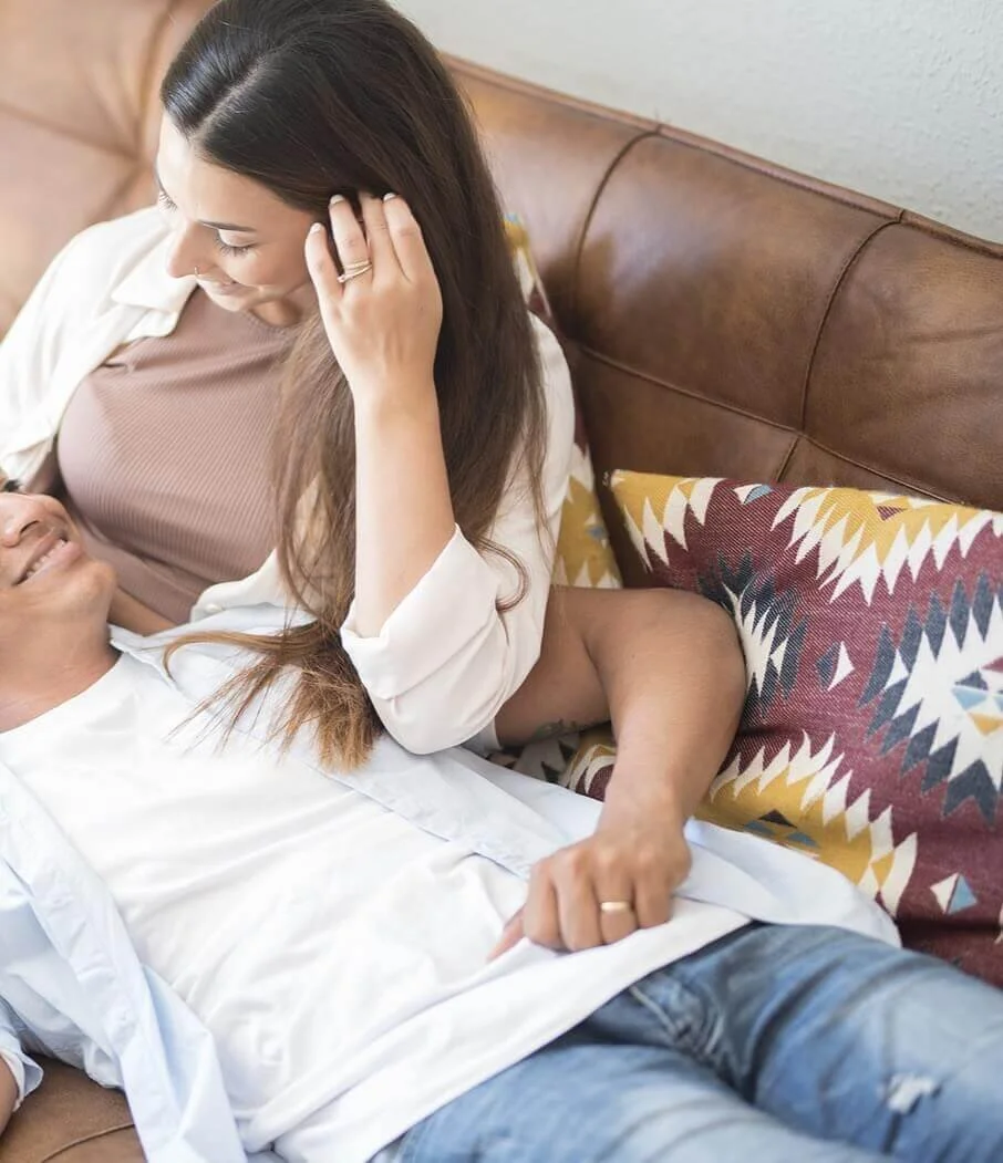 Photo of a happy man laying in his smiling partners lap on a couch. Learn to set healthy boundaries when it comes to intimacy with the help of sex therapy in Atlanta, GA.