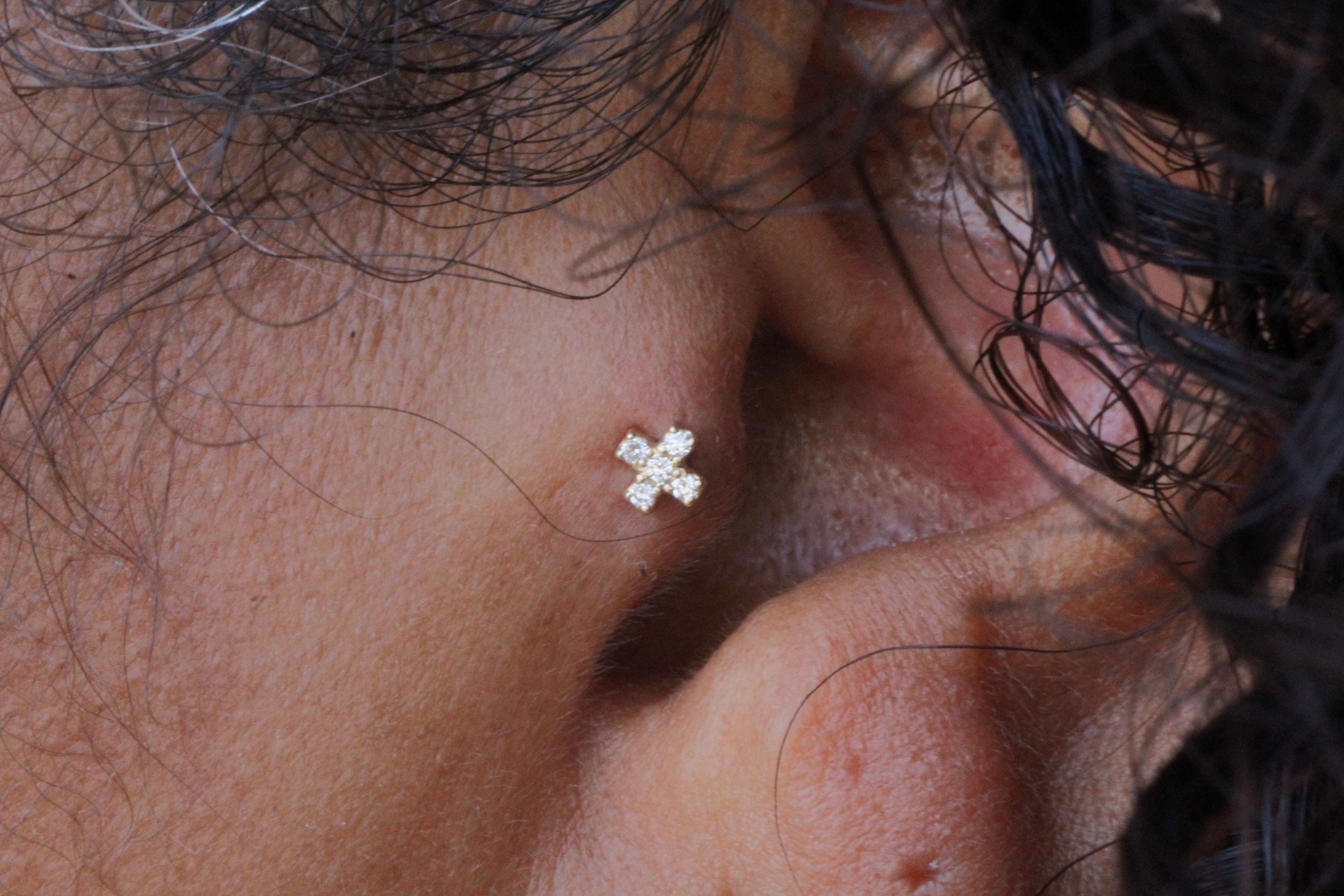 Close-up of a person's new tragus piercing with a yellow gold BVLA "Lois" end with white Swarovski 