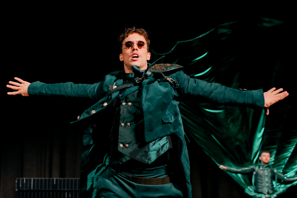 Performer in an emerald costume with a green silk wing on stage at the Emerald Gala