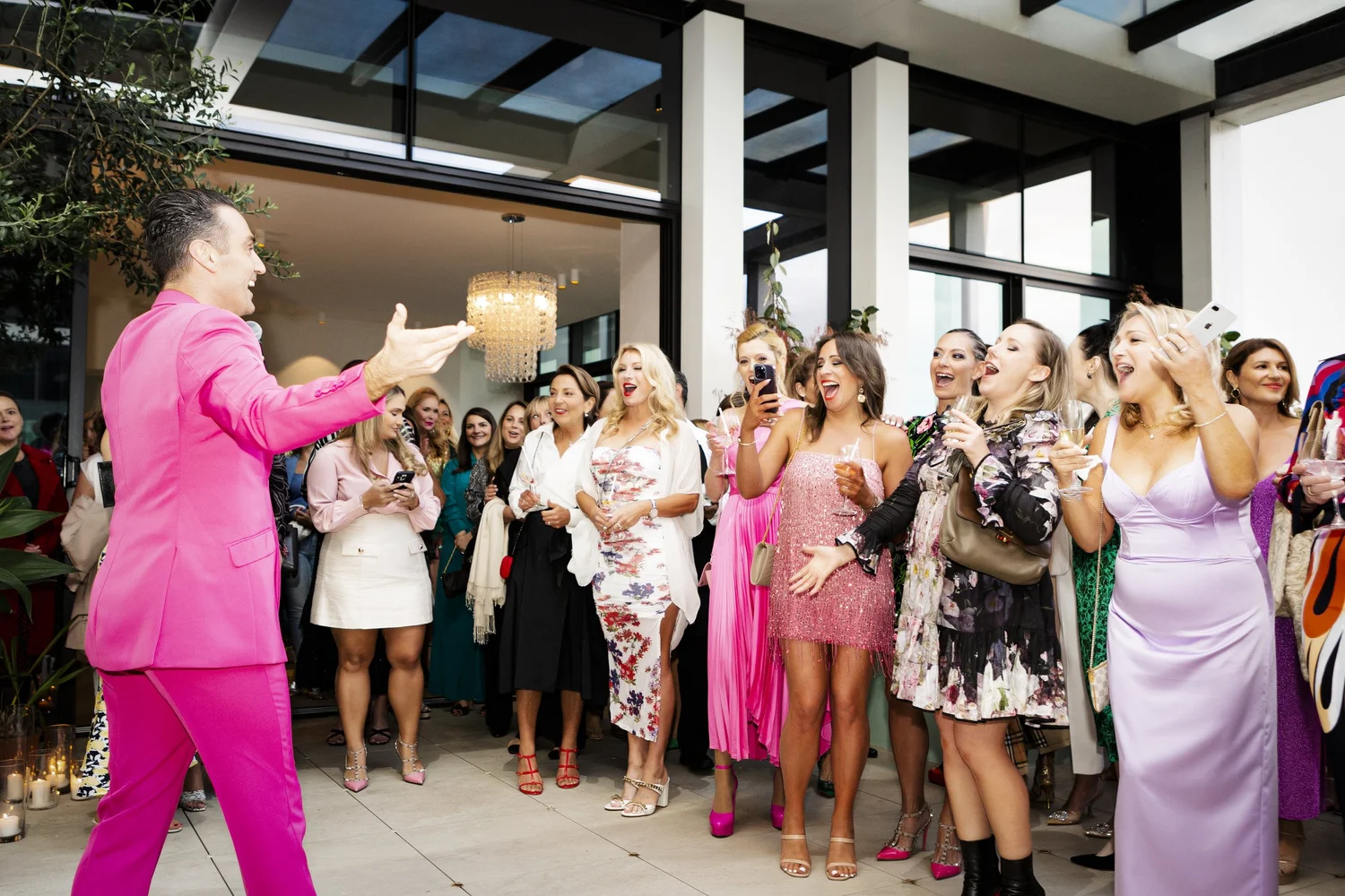 A performer in a hot pink suit entertaining guests at an International Women’s Day celebration