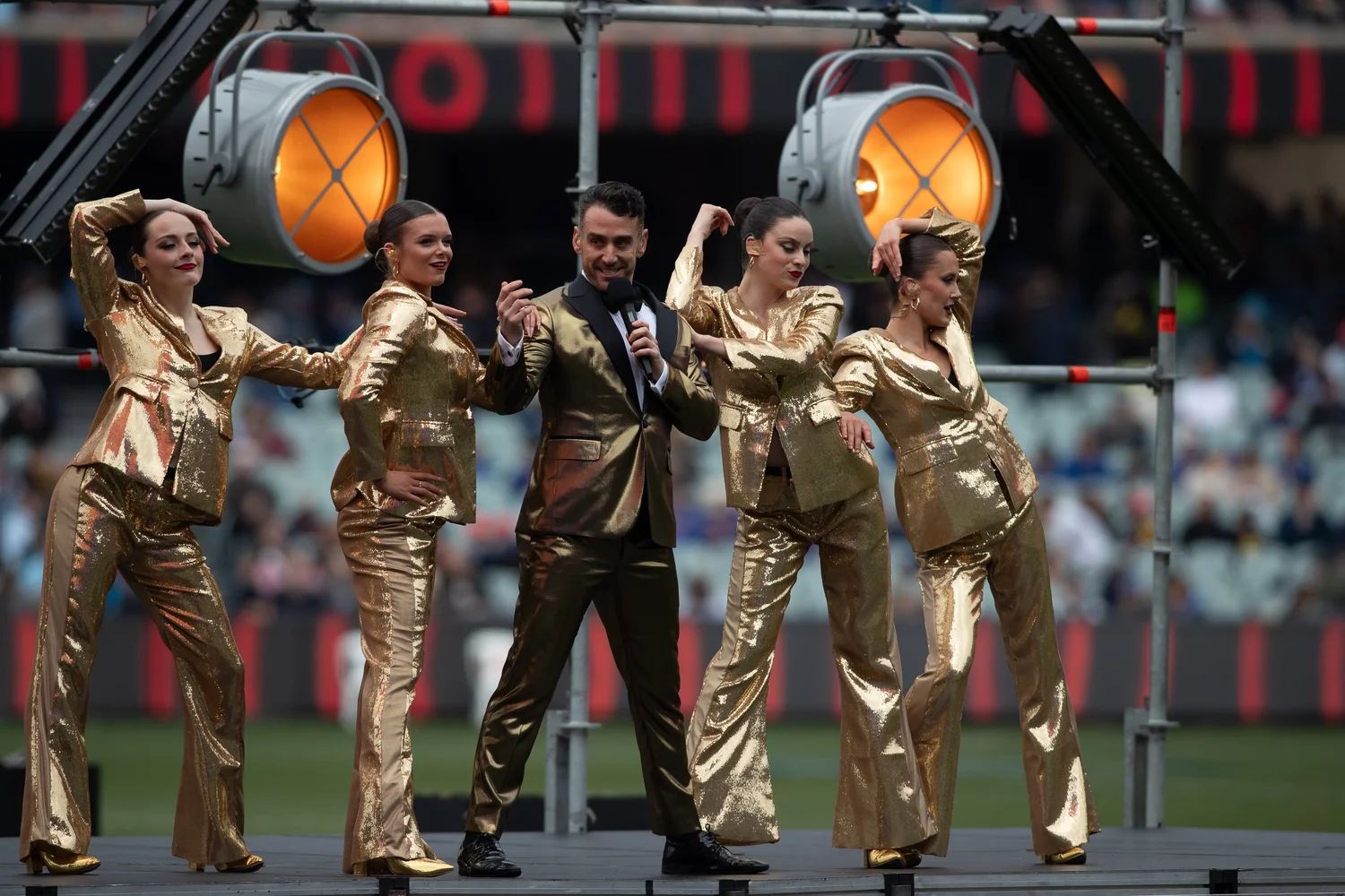 Gold-suited dancers and host performing at Adelaide Oval