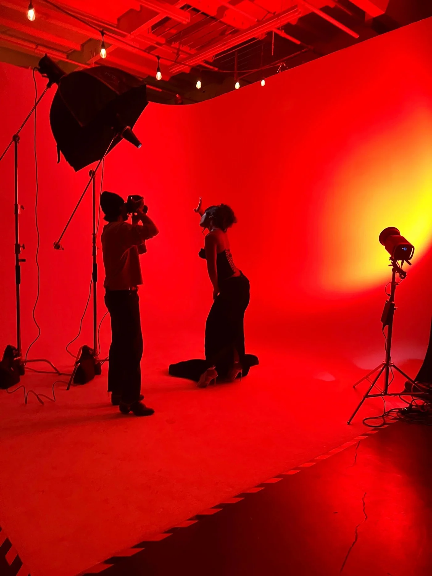 A photographer shooting a model on a cyclorama wall washed in red light