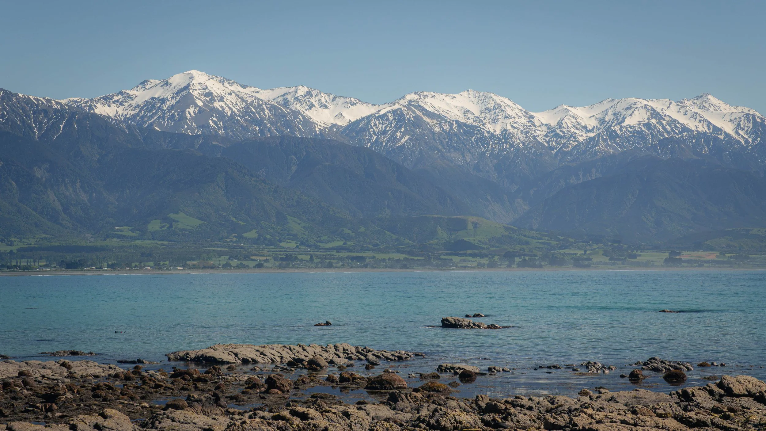 Scenic view of the Kaikōura coastline with mountains and the Pacific Ocean.