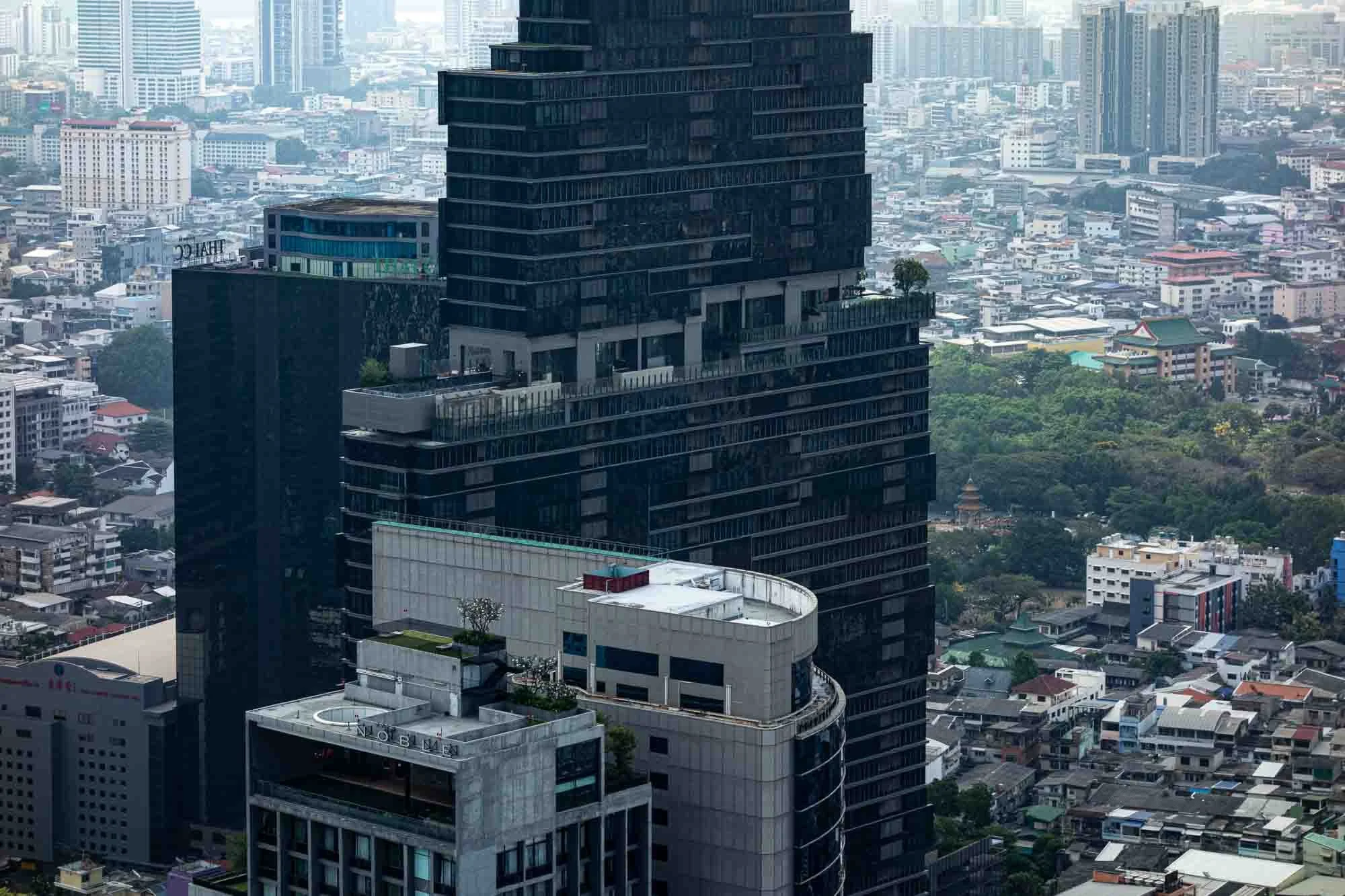 A tall, black office building with modern architecture surrounded by other buildings in a cityscape.