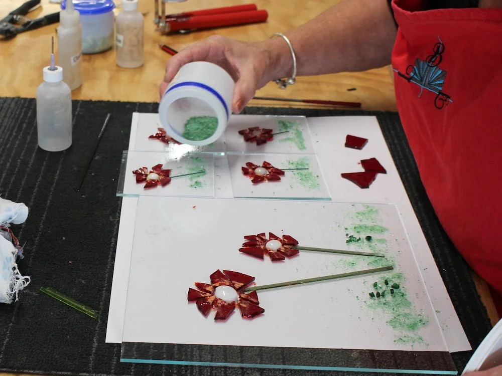 A student adding frit to their fused glass platter