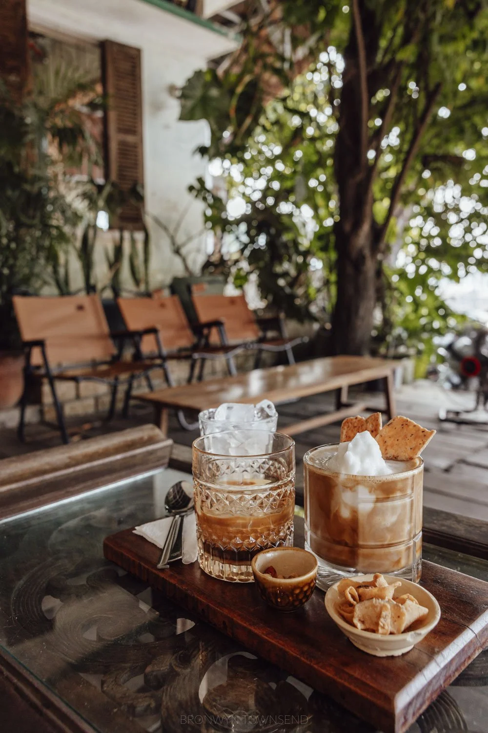 two iced coffees in glasses on a wooden tray at a cafe in hue