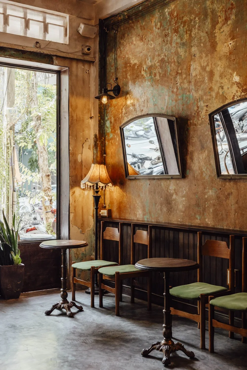 Vintage-inspired interior with art deco mirrors, green velvet dining charies, and dark wooden tables at Tan. Coffee shop, Hue