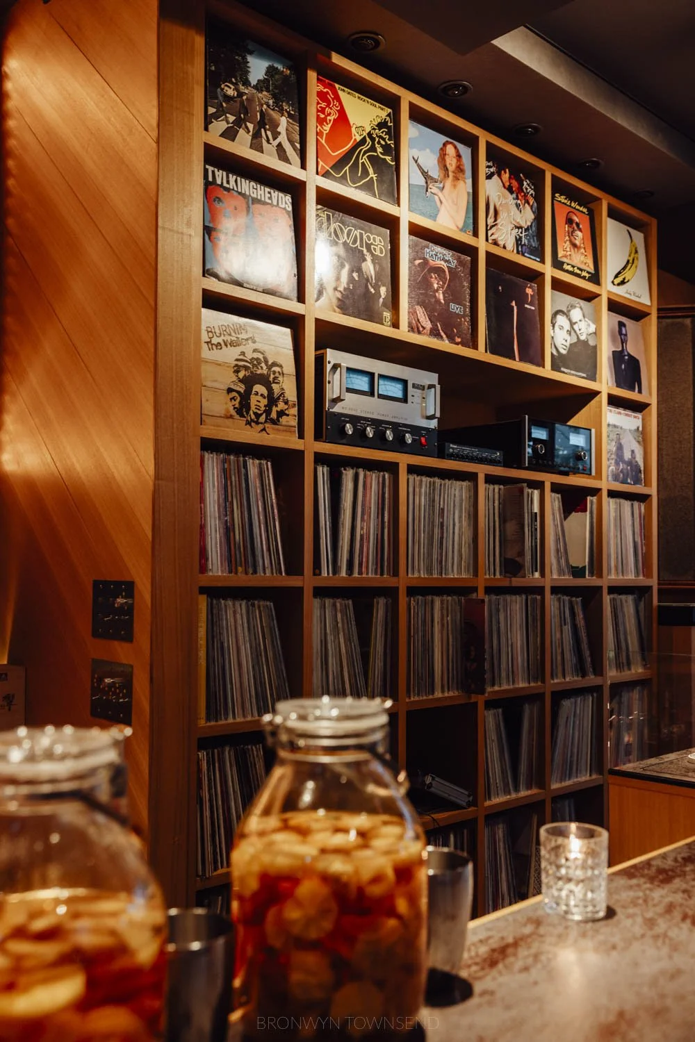 A wall of vintage vinyl records set in a wood wall of a bar at Kanazawa music bar