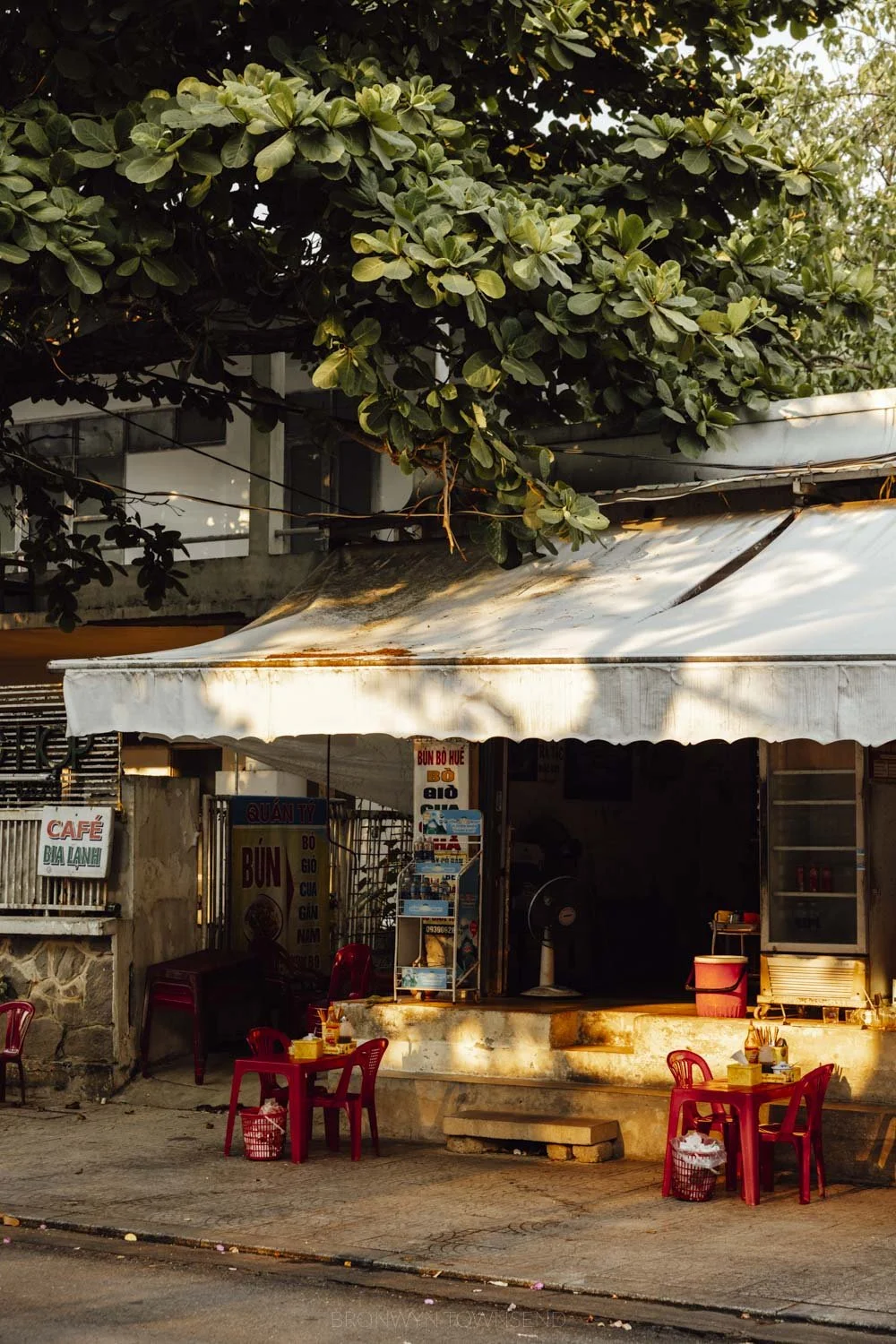 A storefront at sunset with two small red plastic tables with matching stools in Hue, vietnam