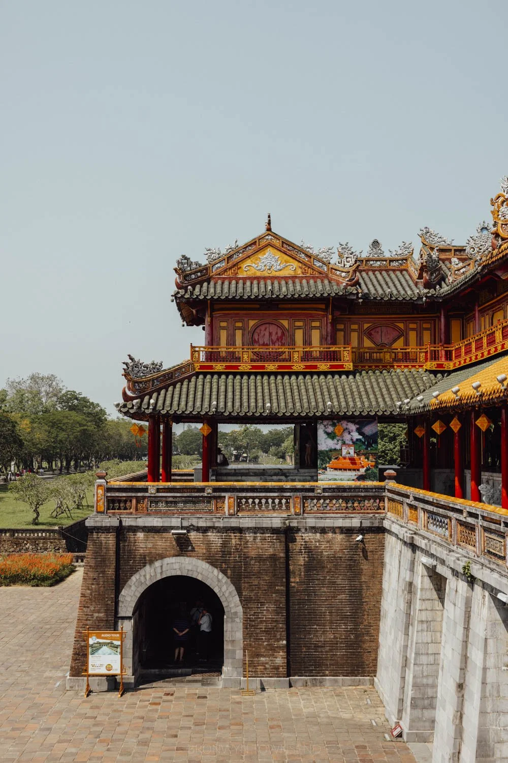 A side on perspective one one side of the grand meridian gate detailed in traditional vietnamese architectural style on a blue sky day