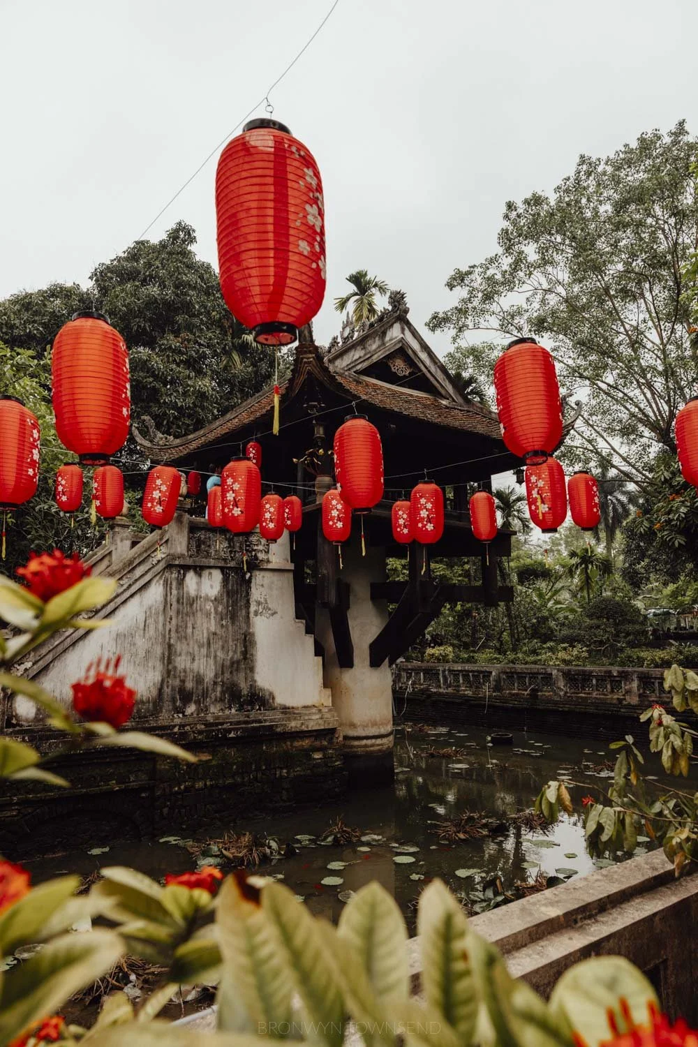 one pillar pagoda at ho chi minh complex in hanoi, surrounded by pond and red lanterns strung