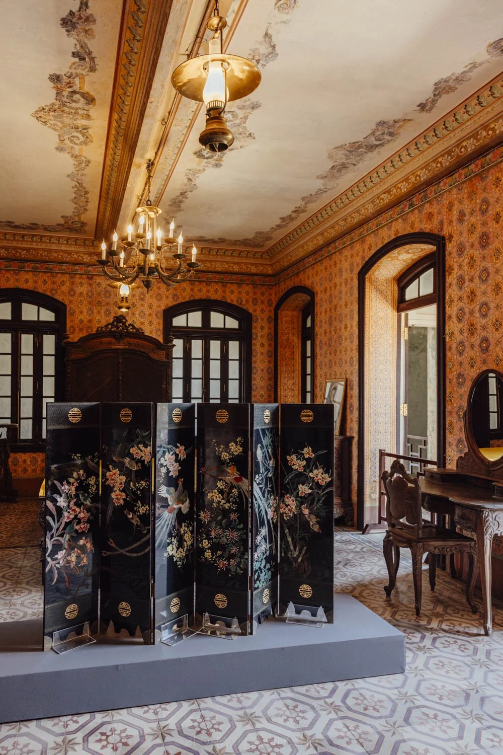 A folded privacy wall in black with vietnamese details in a 20th century wall papered interior