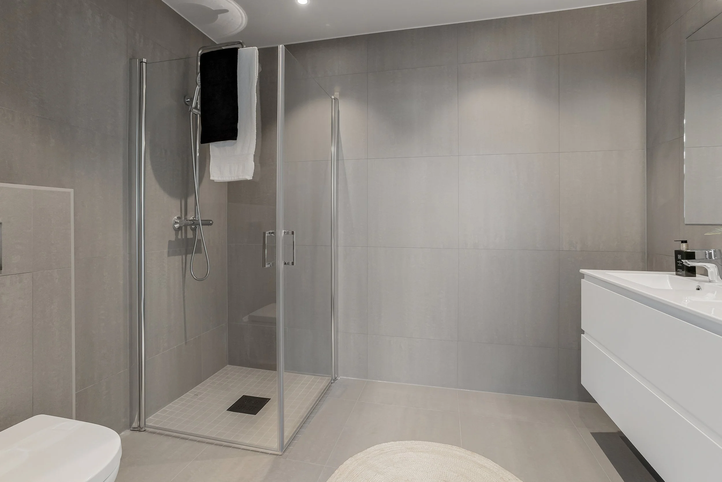 Badet er helfliset med store, moderne fliser og har en romslig dusjsone.