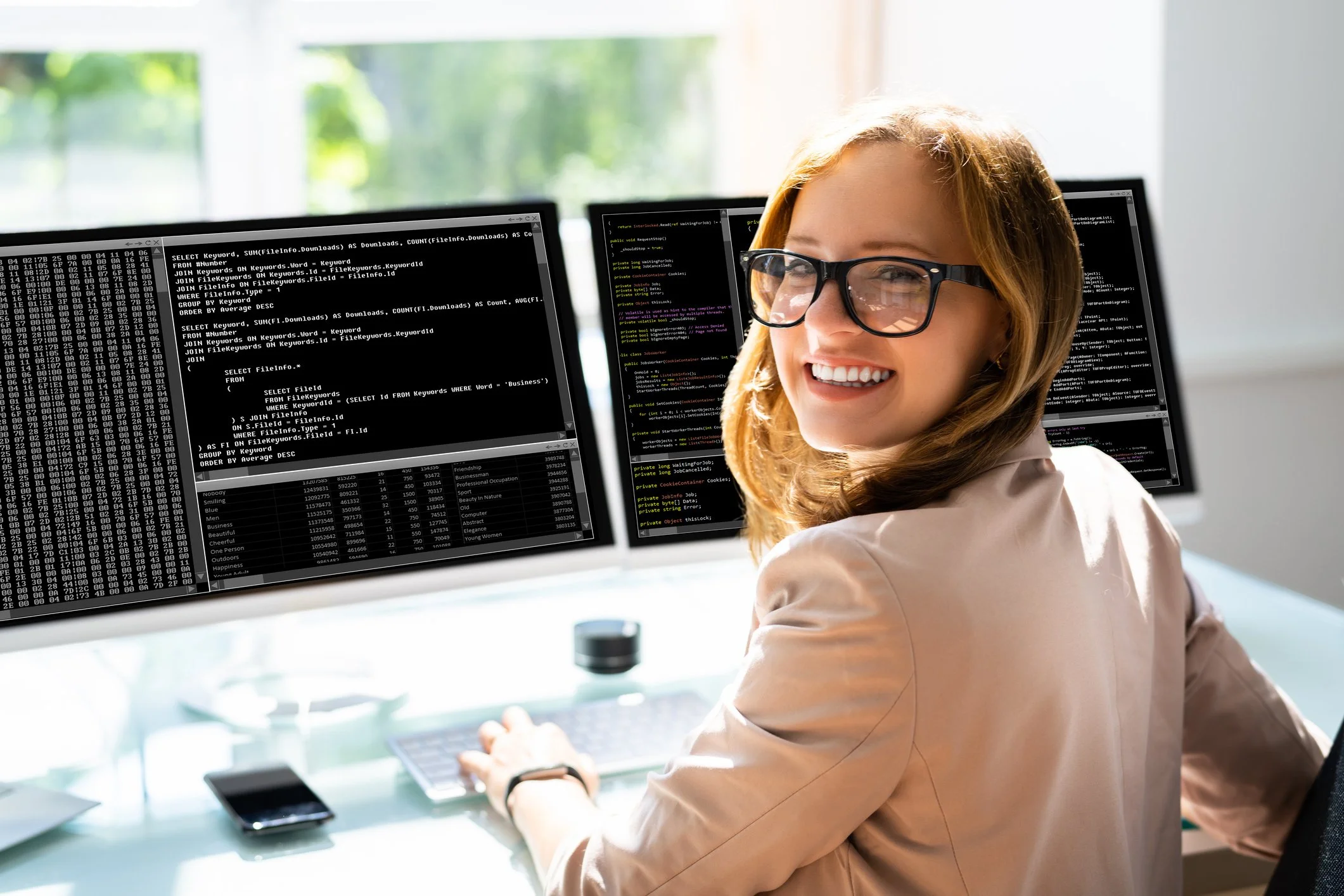 Informatikerin vor zwei Computerbildschirmen