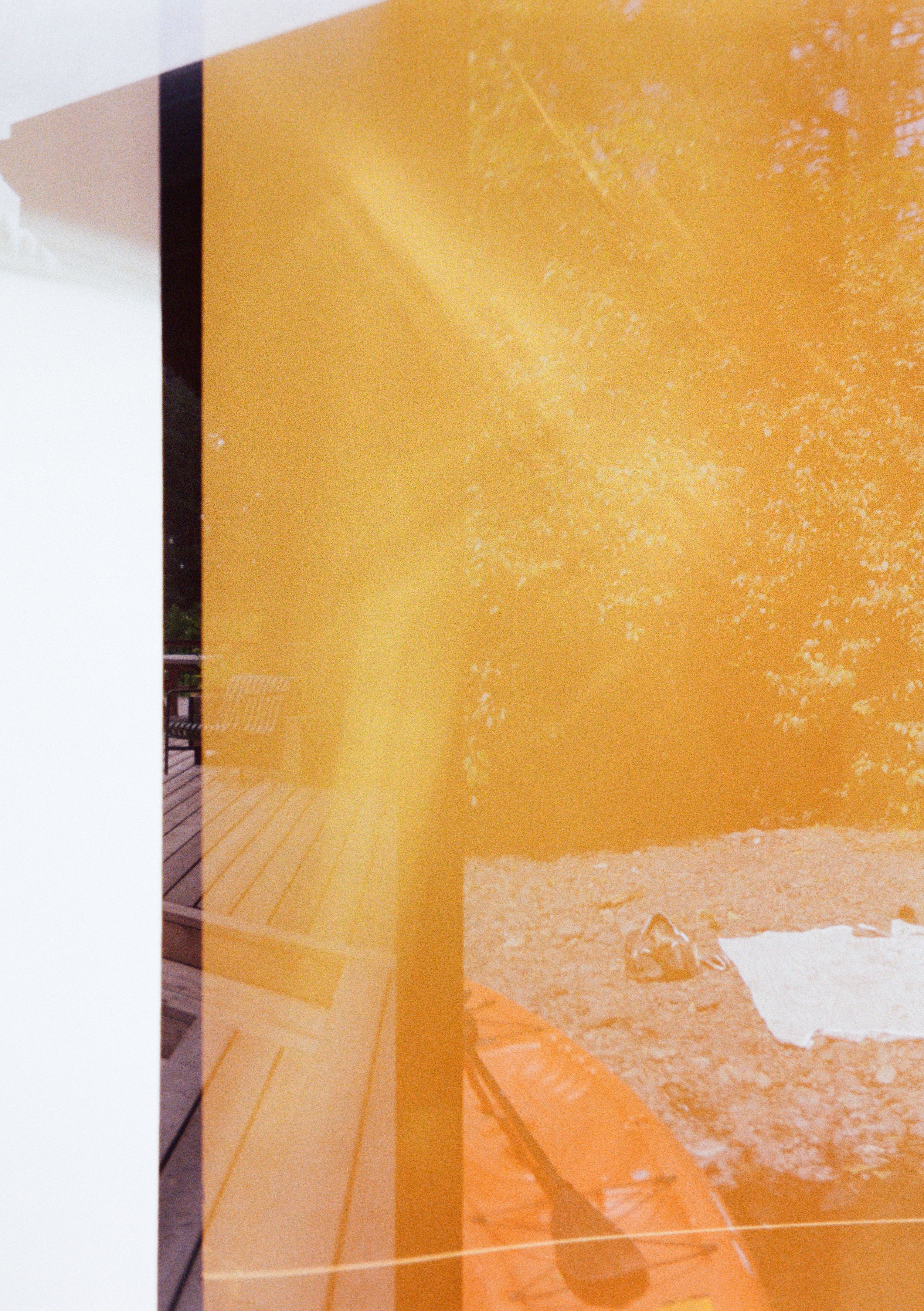 Reflection of outdoor picnic scene with a tree on a yellowish-orange reflective surface, with a white napkin and shoes on the ground.