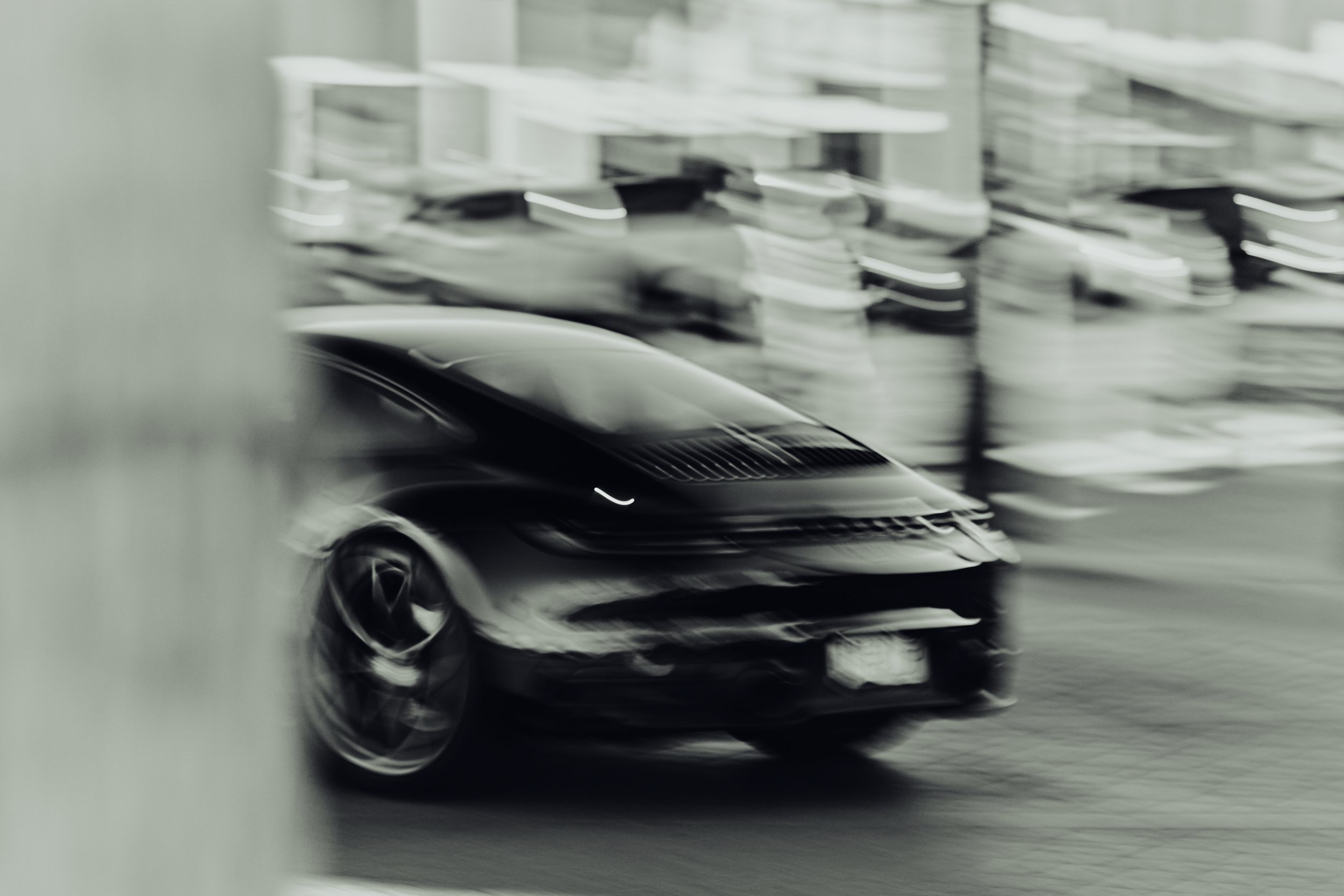 Blurred black sports car driving in an urban environment.
