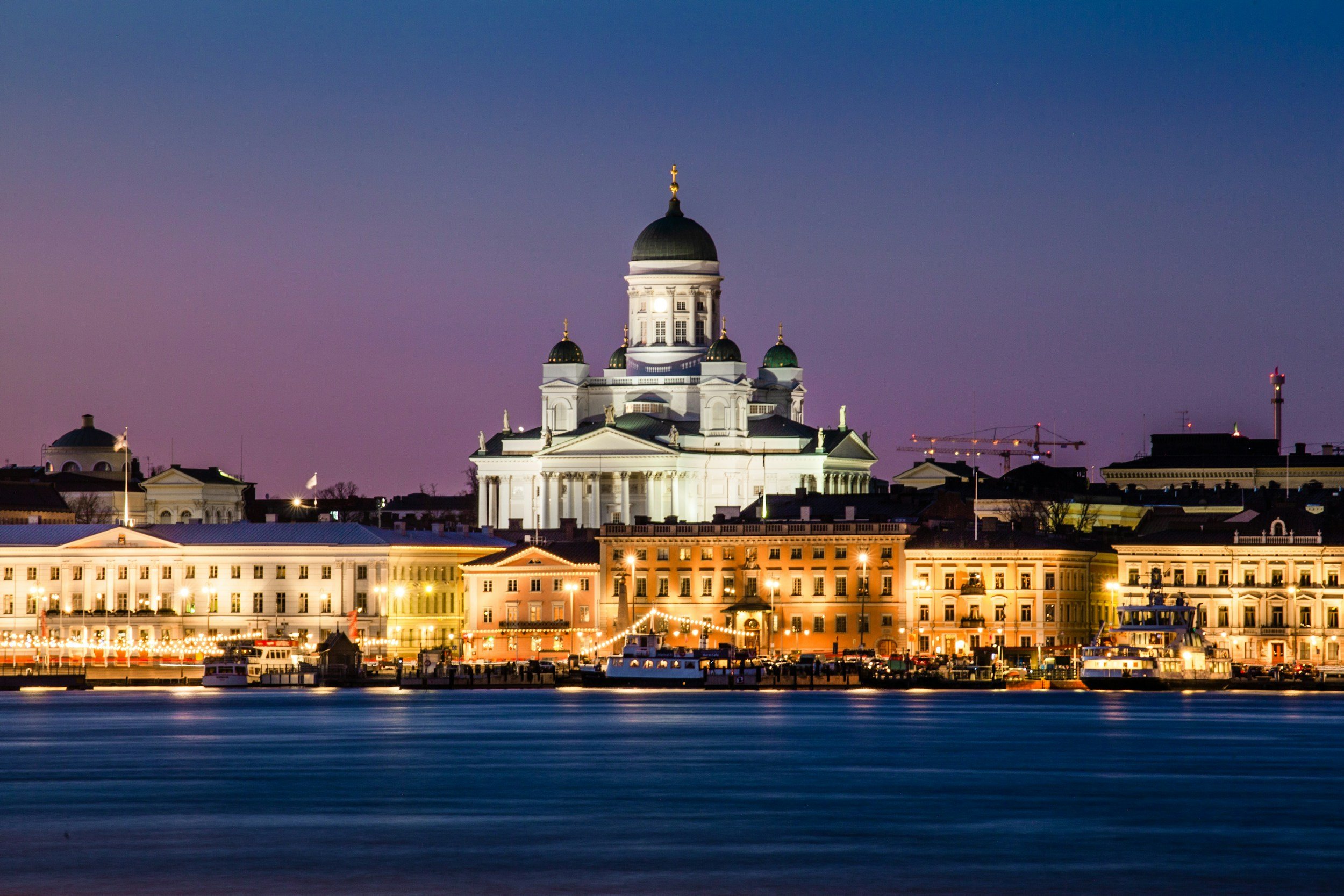Nighttime view of Helsinki Cathedral in Finland, illuminated and reflected on the water.