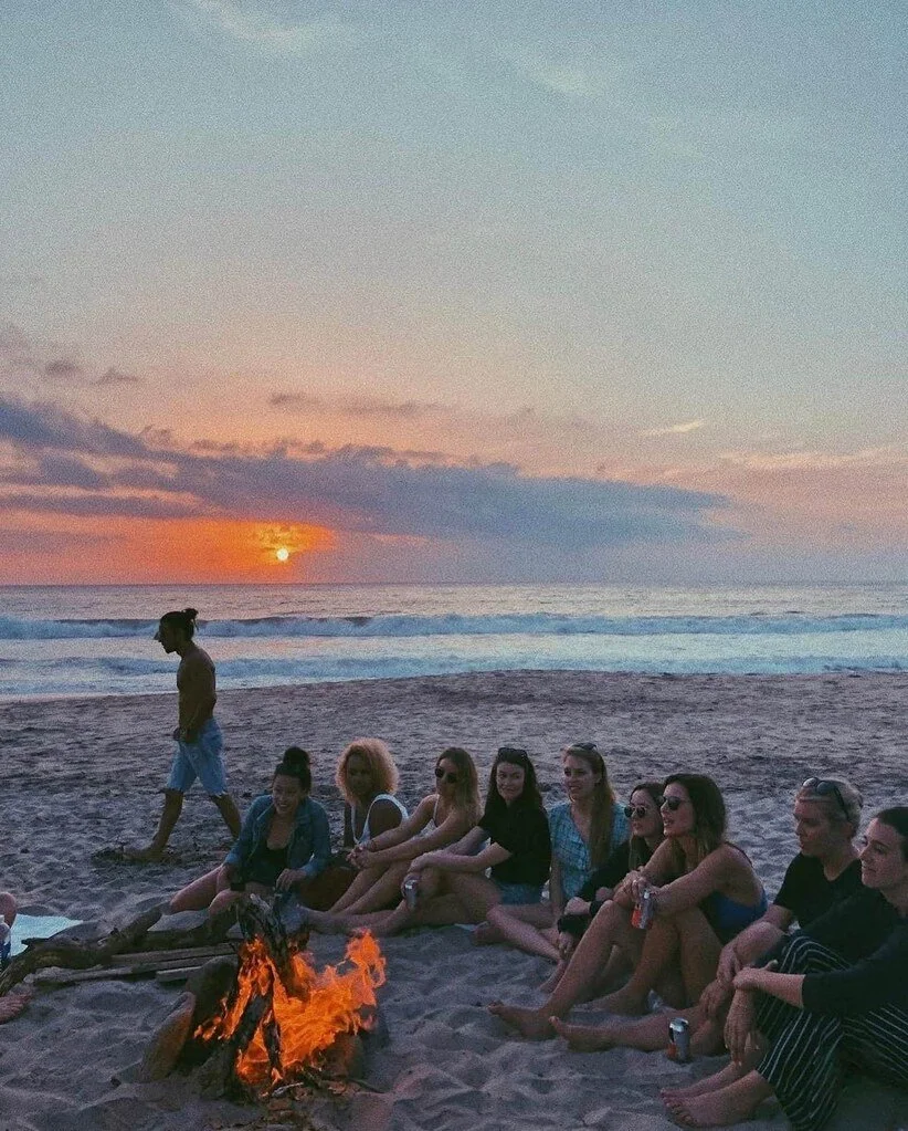 Friends gathered around a beach bonfire at sunset in Sayulita Mexico.