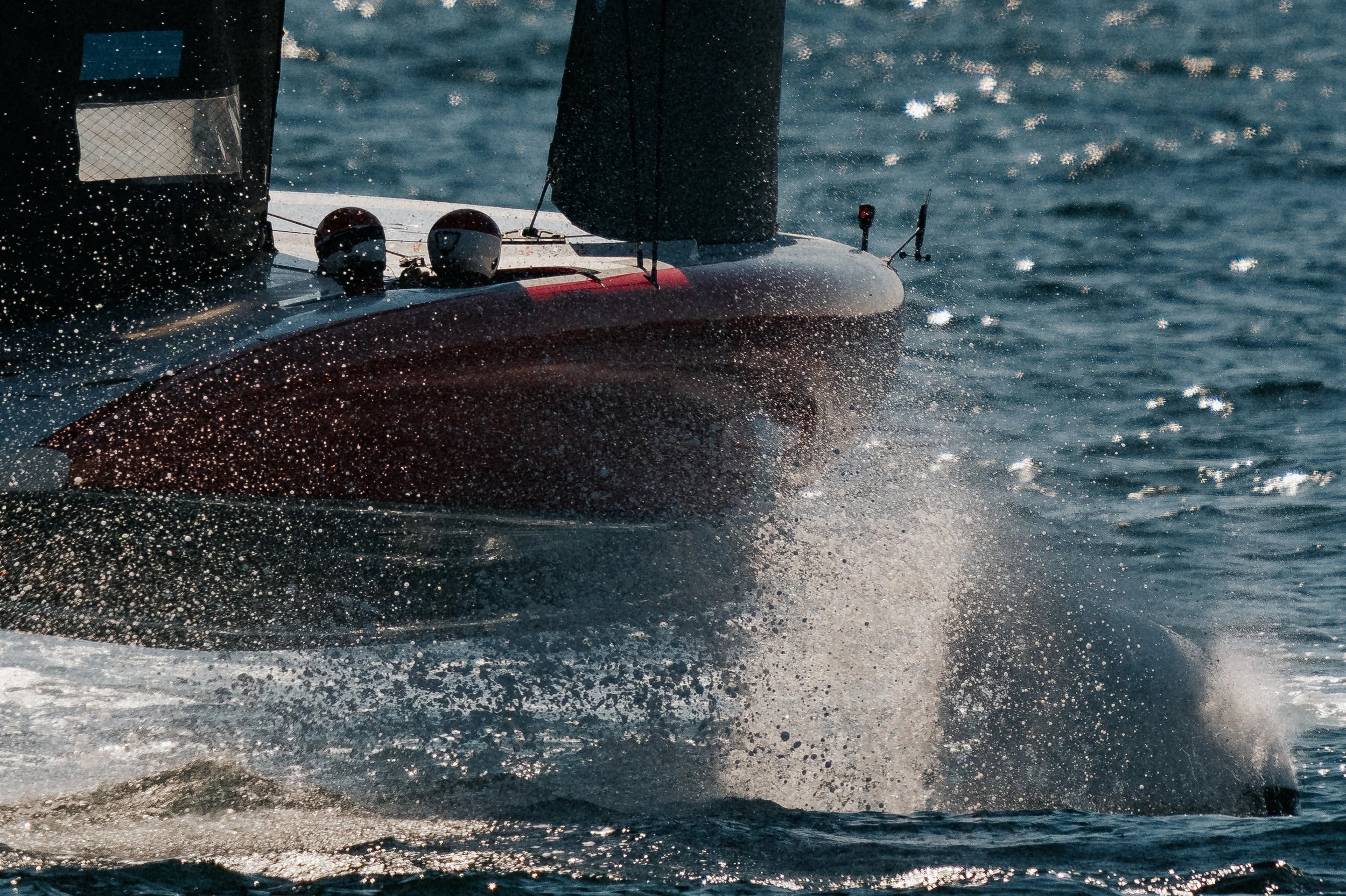 Speedboat speeding through water with water spray and sunlight reflection.