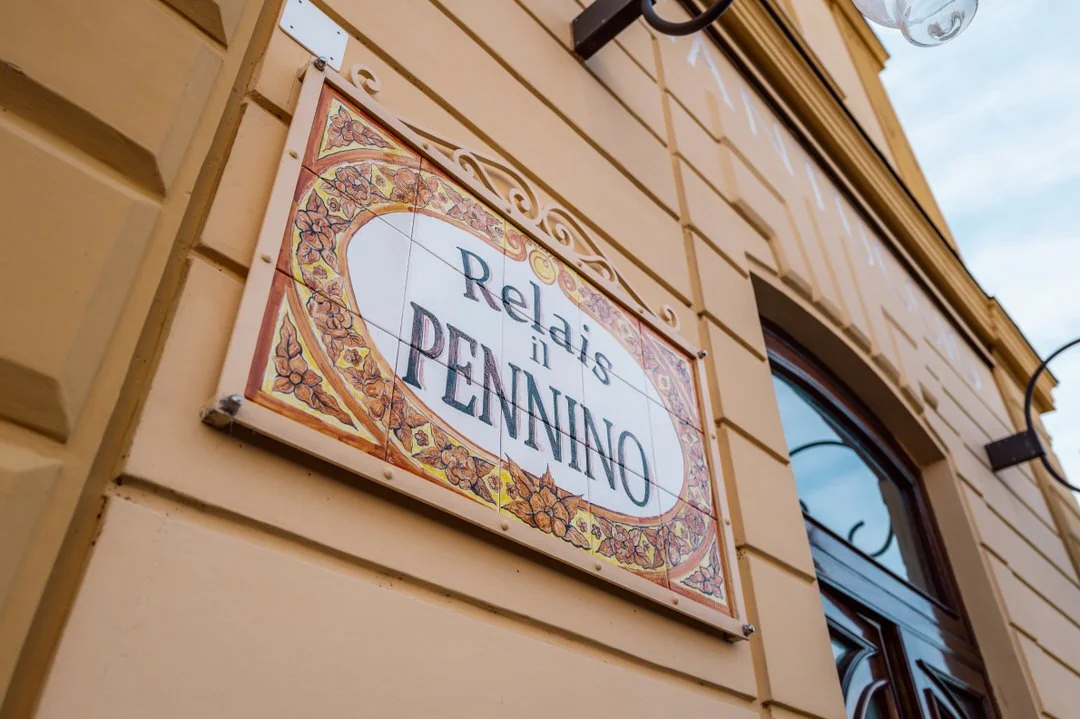 A decorative sign on the wall of a building that reads "Relax in PINNAO" with colorful floral border and ornate patterns.