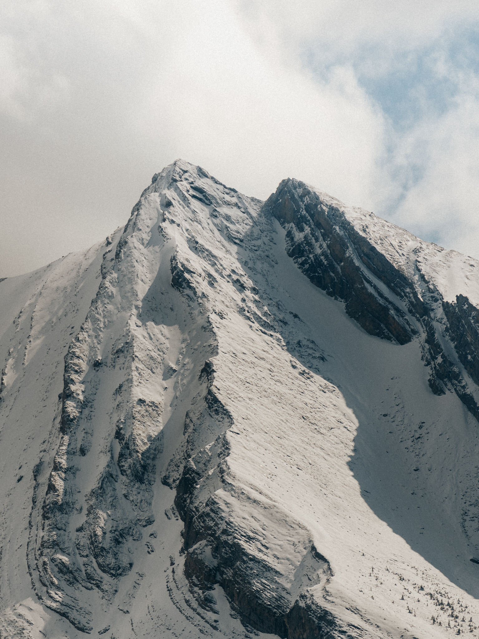 Snow-covered mountain peaks under a cloudy sky.