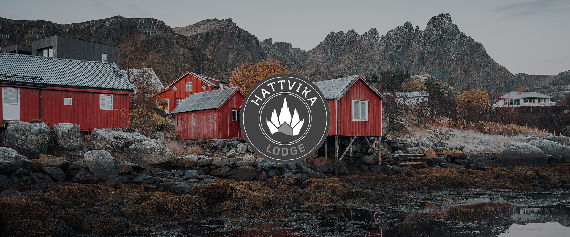 A landscape of mountains and rocks with red houses on the shoreline, and a lodge logo in the center.
