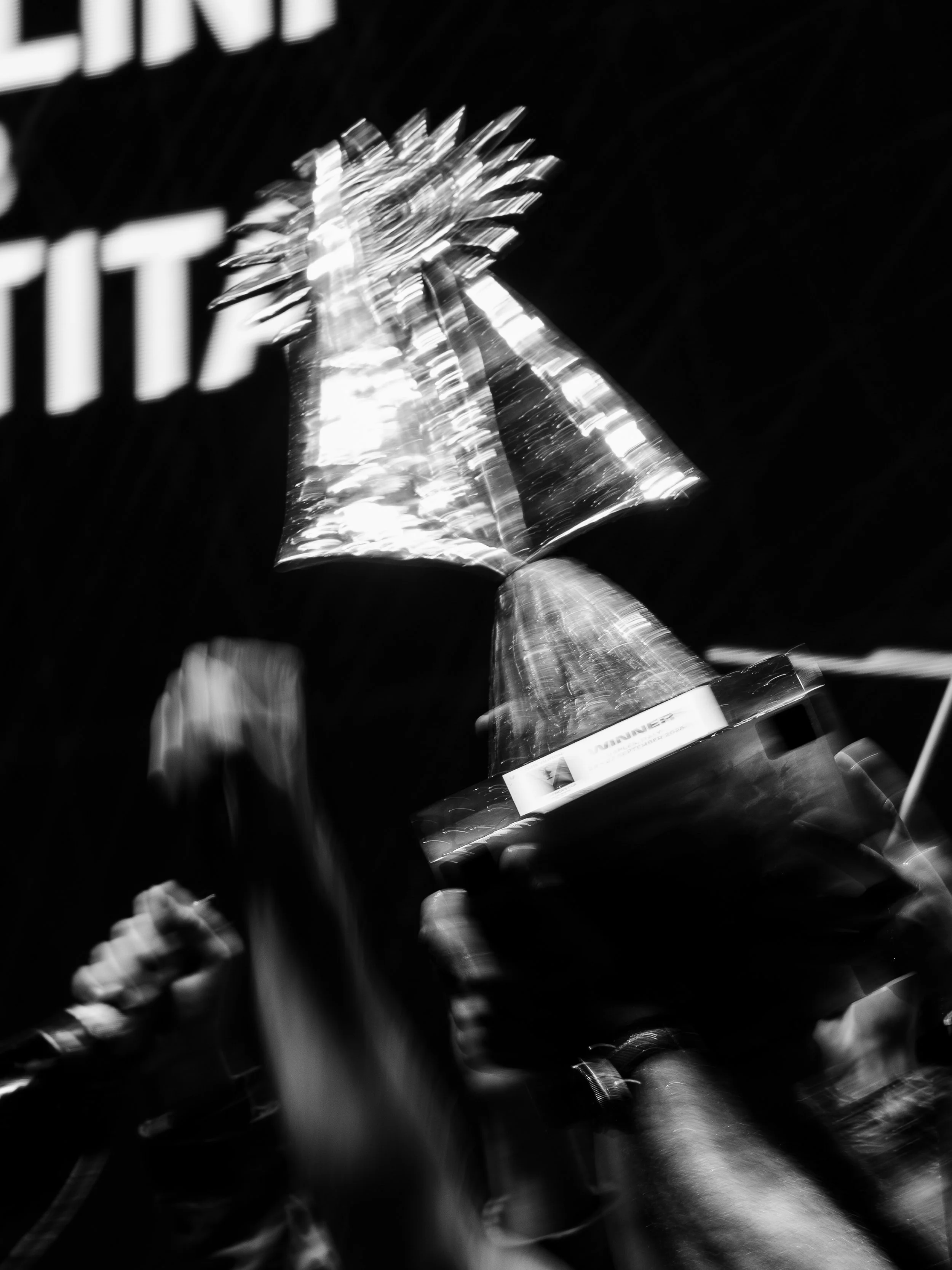 A close-up black and white photo of a trophy with a star on top, with a blurred background.