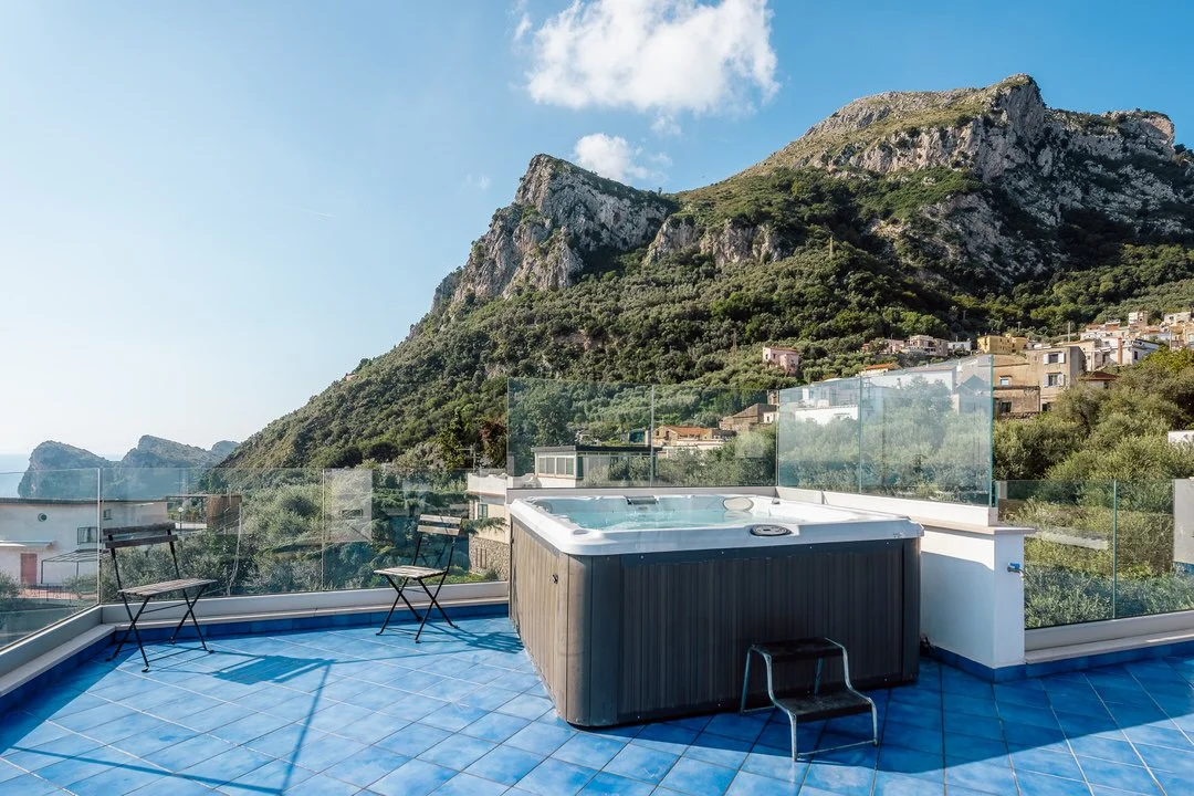 Rooftop with hot tub, two chairs, and mountain view