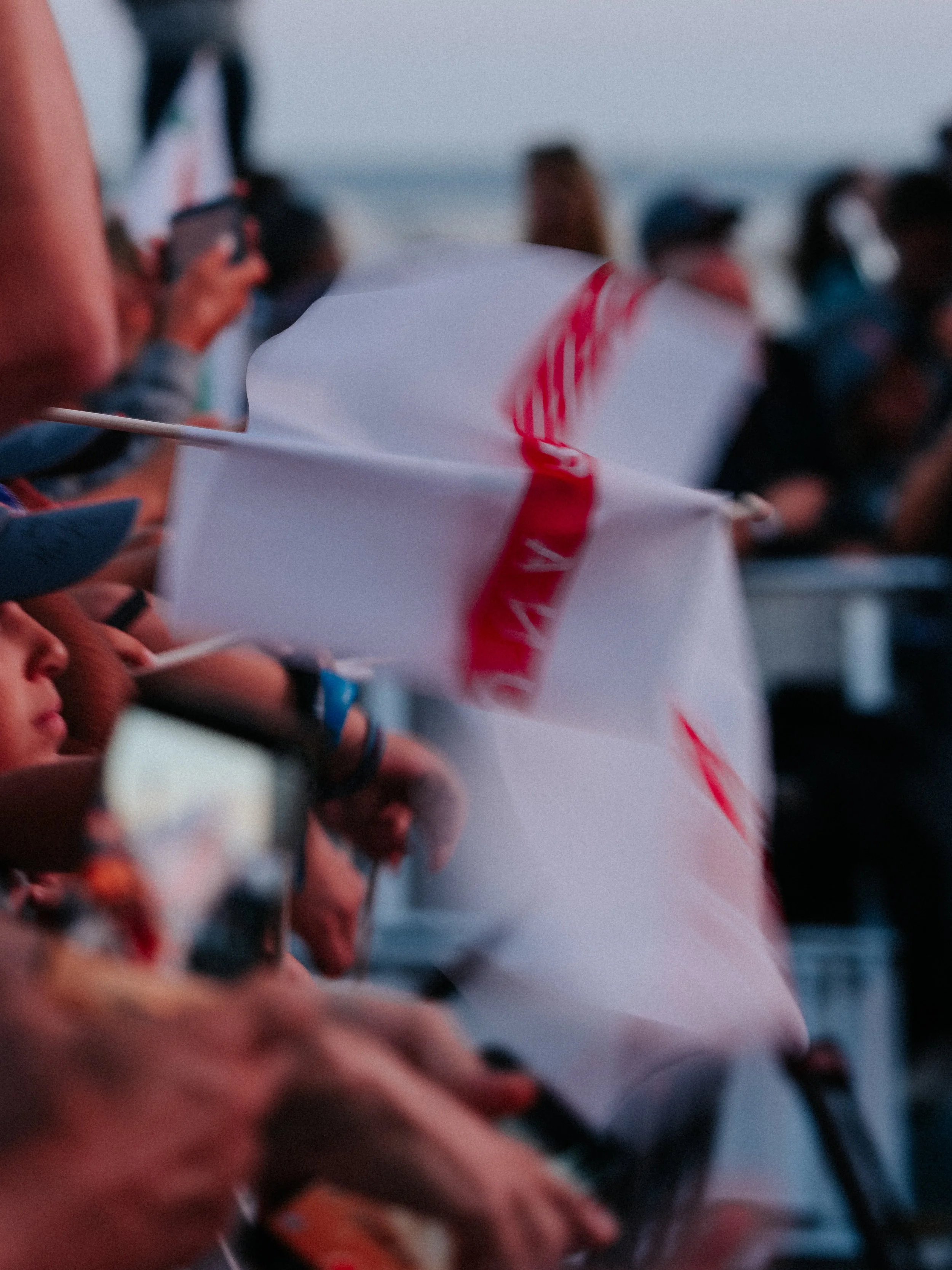 A group of people on the beach holding a white flag with a red stripe.