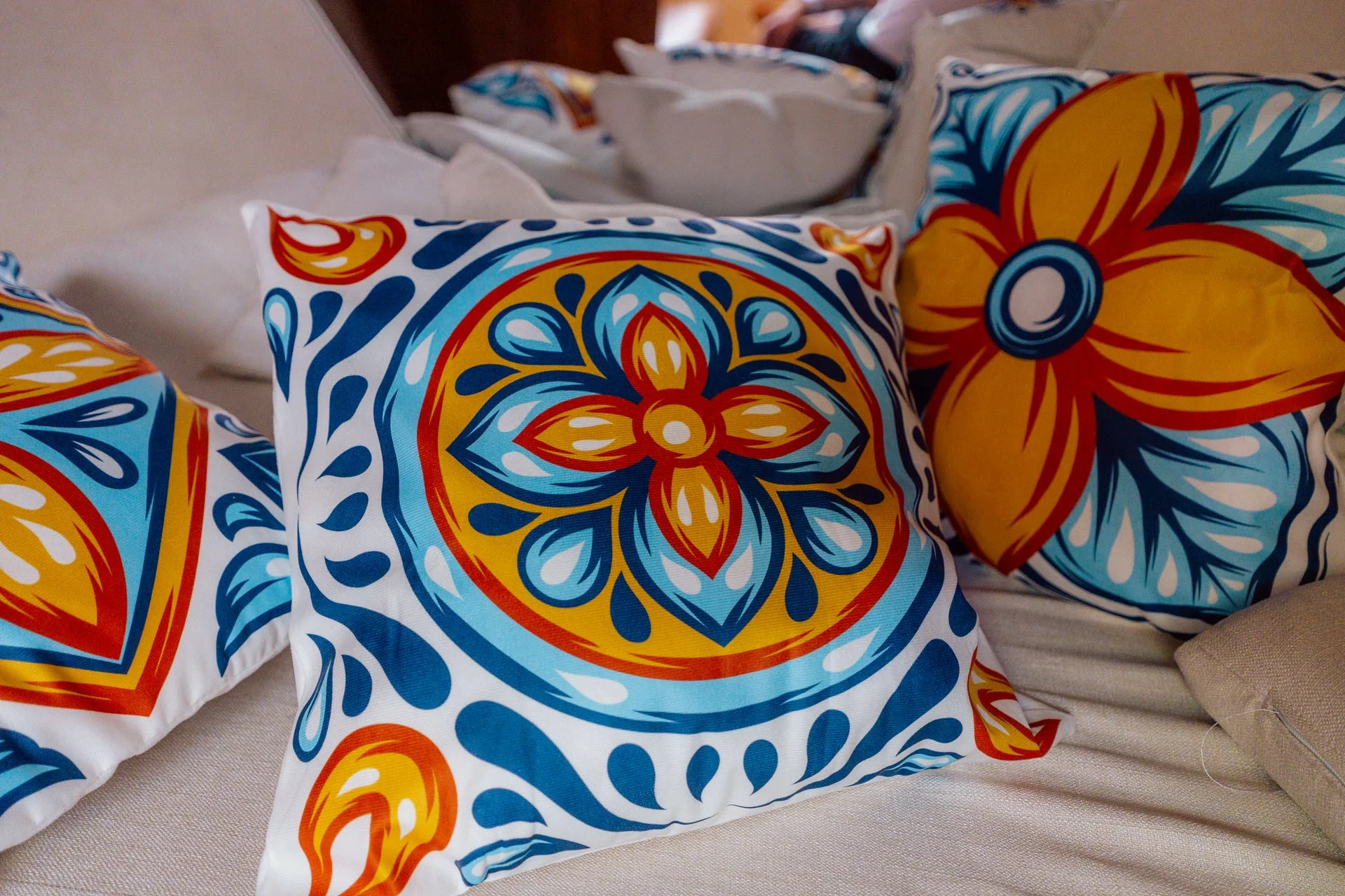 Colorful decorative pillows with floral patterns in blue, yellow, orange, and red, placed on a sofa or bed.