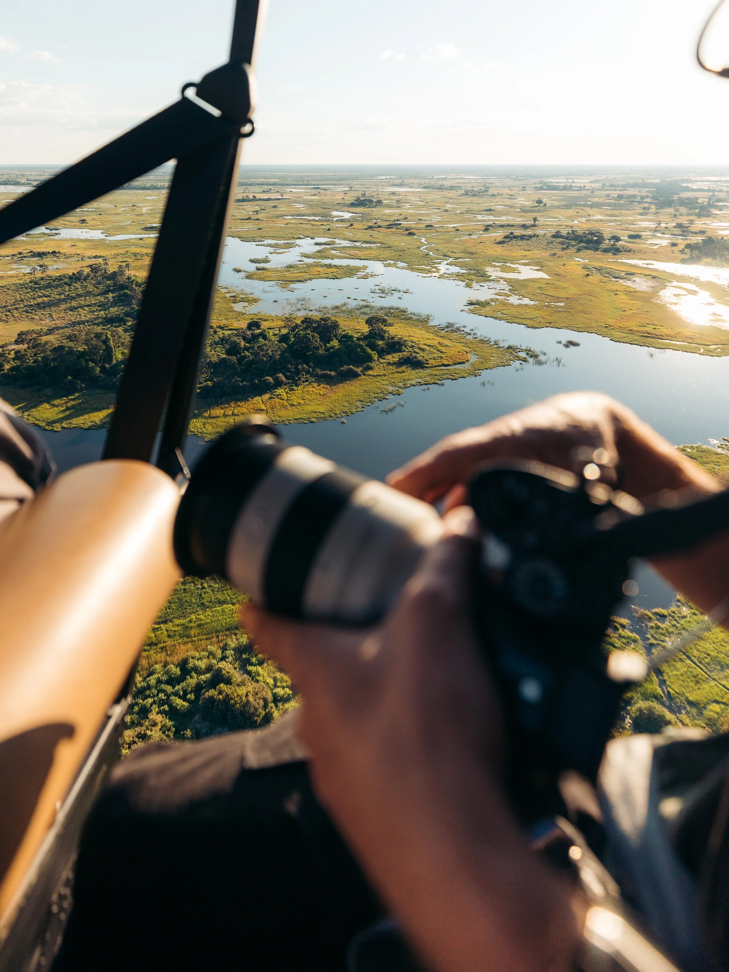 Aerial view of wetlands and lakes with patches of green vegetation seen from a helicopter.
