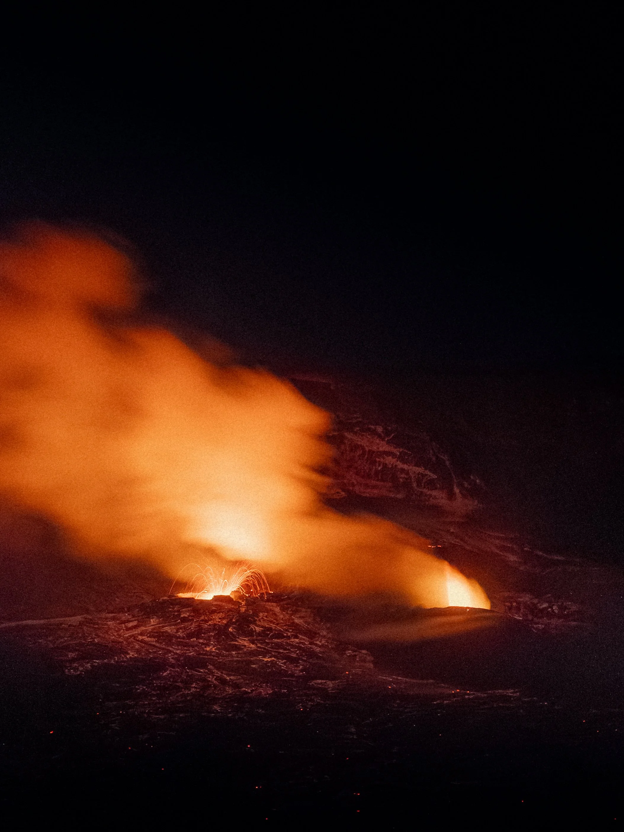 Nighttime eruption of a volcano with lava and smoke rising into the dark sky.
