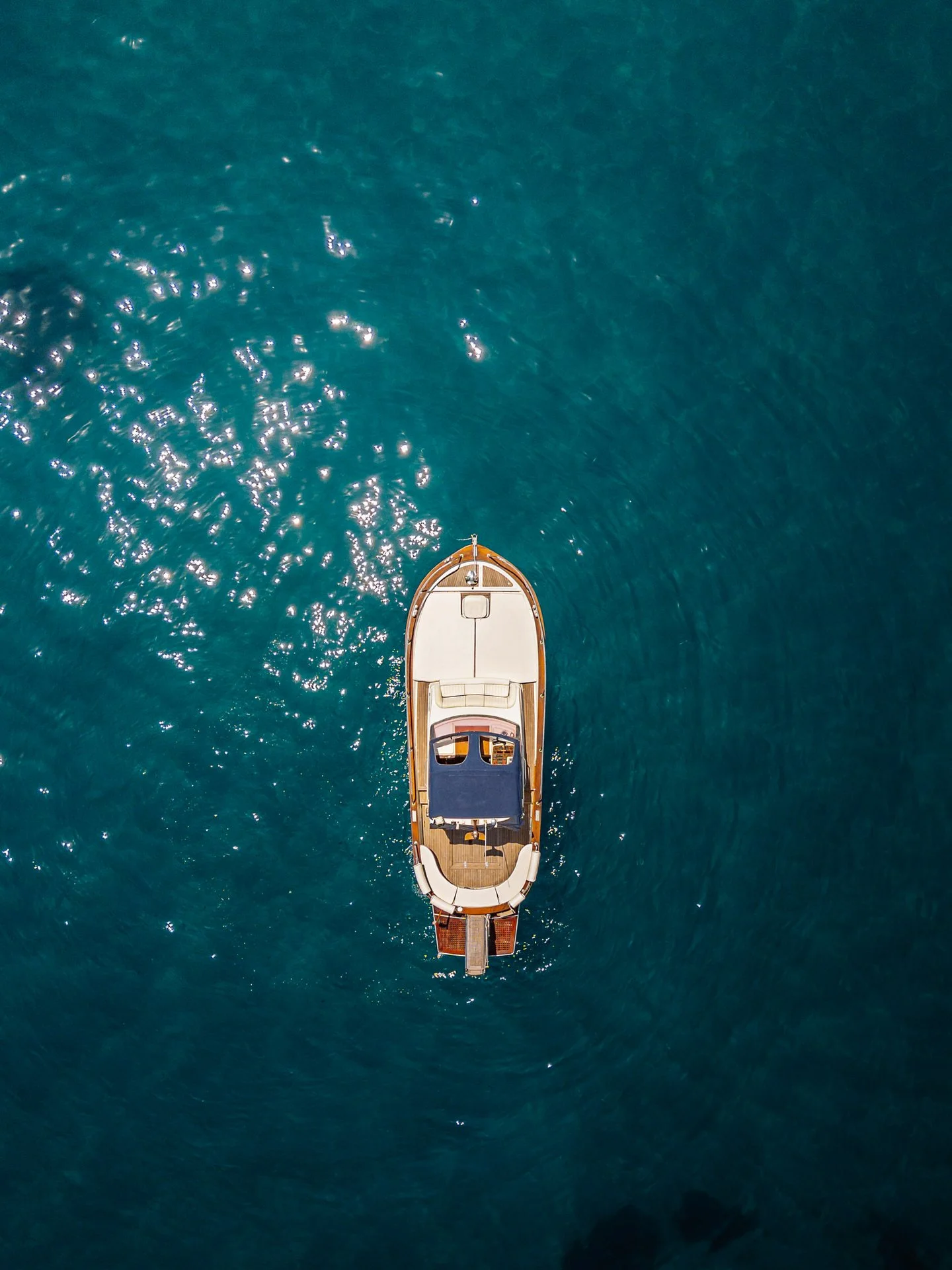 Aerial view of a yacht floating on blue ocean water.