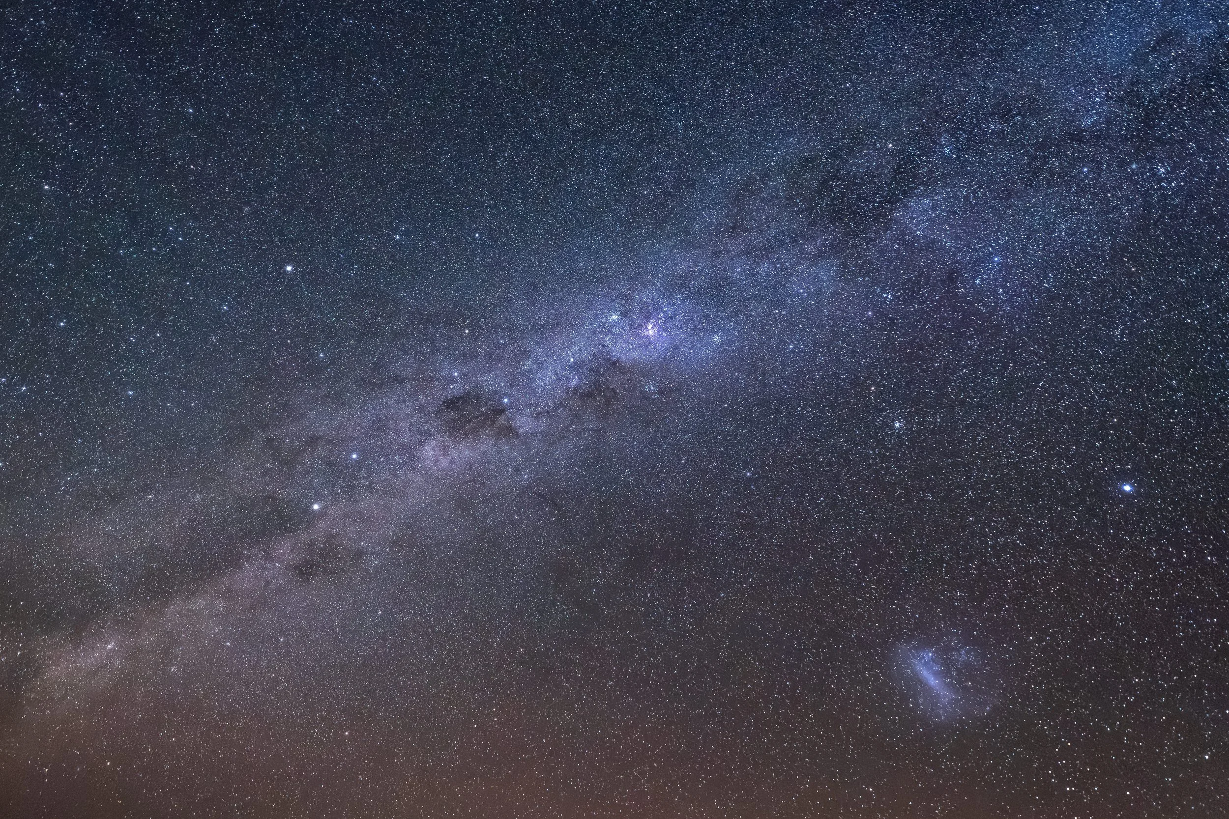 A clear night sky filled with countless stars and visible celestial objects, including the Milky Way galaxy.