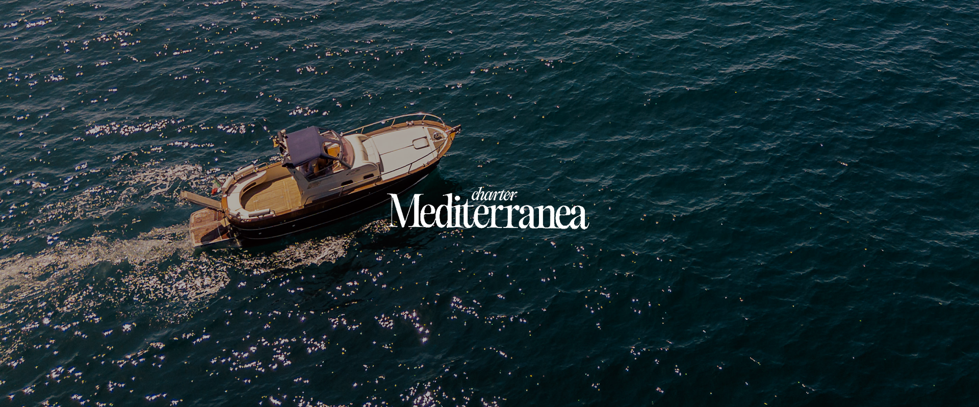 Aerial view of a boat on the sea with the text 'Charter Mediterranea' overlaid.