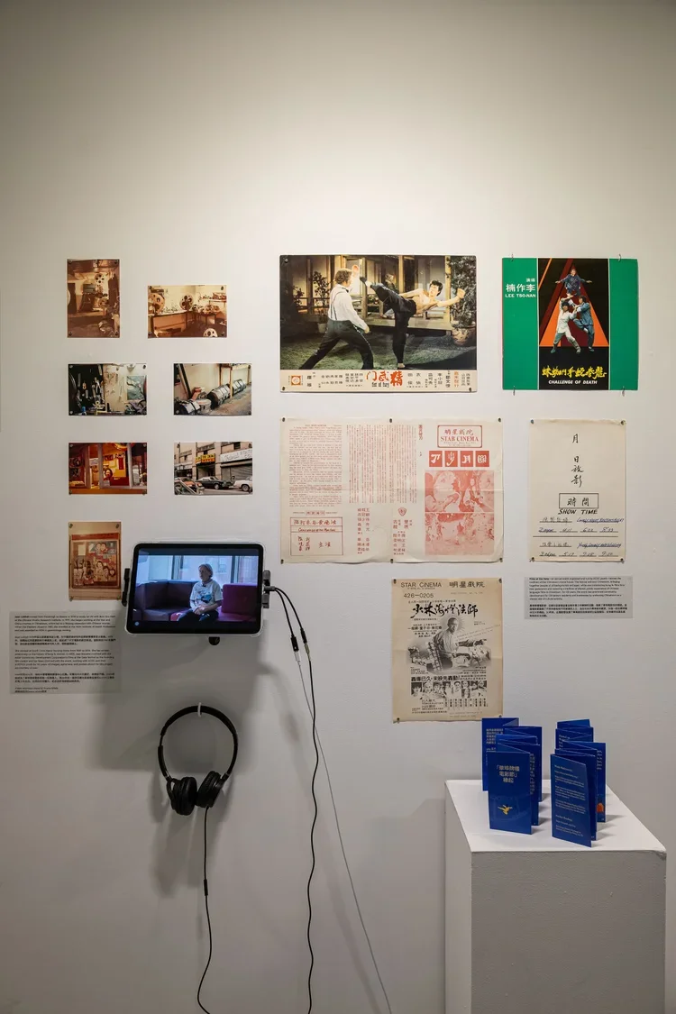 Wall exhibit with vintage movie posters, photographs, a tablet showing a woman sitting, and informational text in Chinese, with a stand holding blue pamphlets.