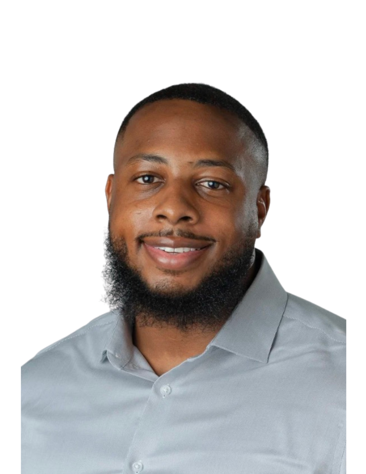Portrait of a smiling African American man with short hair and a beard, wearing a light gray collared shirt against a white background.