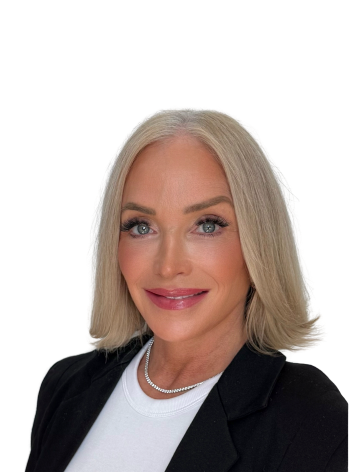 A woman with blonde hair, blue eyes, and a bright smile wearing a white top, black blazer, and a pearl necklace, posing against a plain white background.